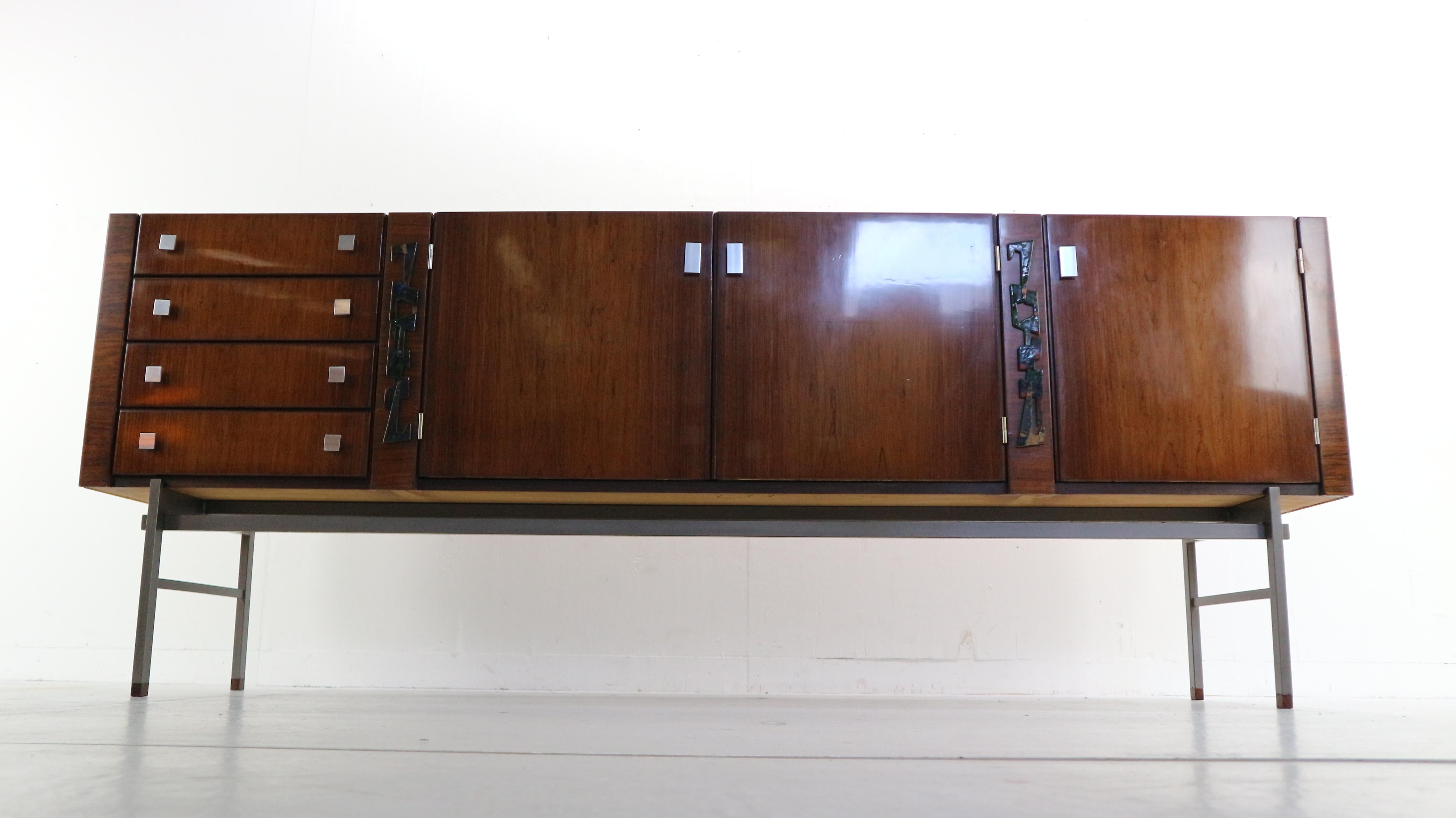 Sideboard design by the architect Alfred Hendrickx in 1960s, Belgium.
This extra large sideboard is made of rosewood and standing on minimalistic metal feet.
Beautiful enameled art details on the sides.
Due to CITES regulations the shipping