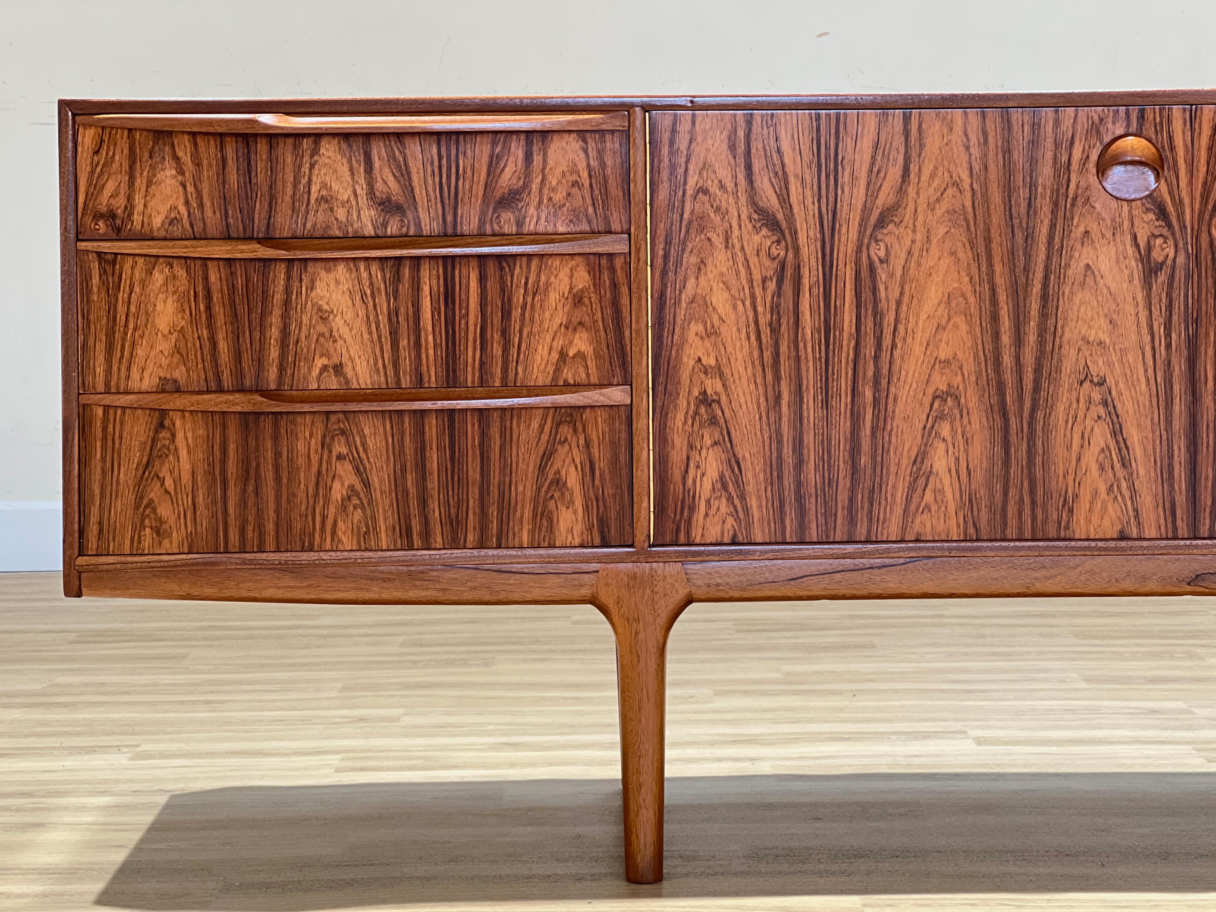 Tom Robertson designed this sideboard for its collection Dunfermline in Scotland for the high-end cabinet maker A.H. McIntosh. The sideboard, handcrafted in stunning rosewood, has all its original features. This sideboard belongs to one of its