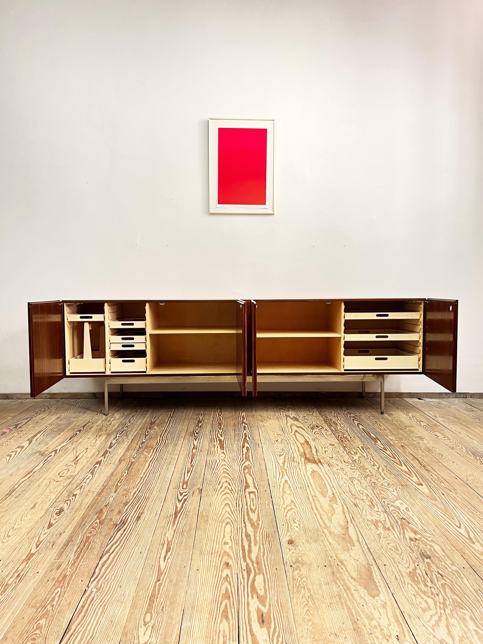 Dimensions 248x56x80 cm (WxDxH)

Elegant Dieter Wäckerlin sideboard in veneer with a strong yet regular grain. The minimalist sideboard sits on a chrome coated metal base with an inlay made out of maple. The credenza comes with lots of storage