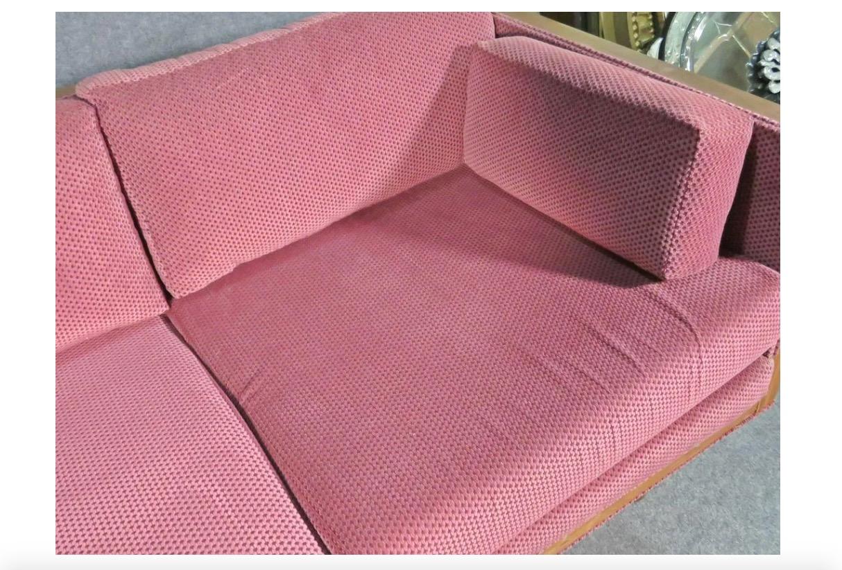 Combining a rosewood frame with unique raspberry-red upholstery, this vintage sofa is a great way to add stylish and timeless Mid-Century Modern design to any room. Please confirm item location with seller (NY/NJ).