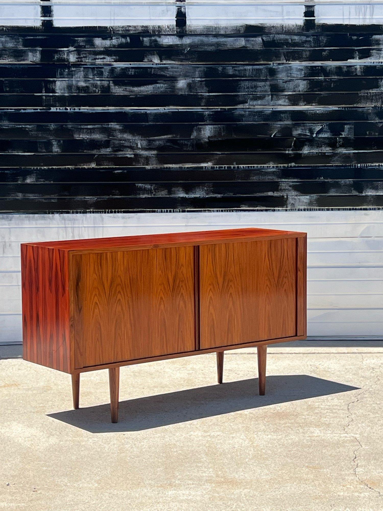 Mid century rosewood tambour door credenza by Poul Hundevad. A striking piece with beautiful exotic rosewood grain. Right side bay features a rolling track open compartment perfect for record storage. Left side has adjustable shelving. Tambour doors