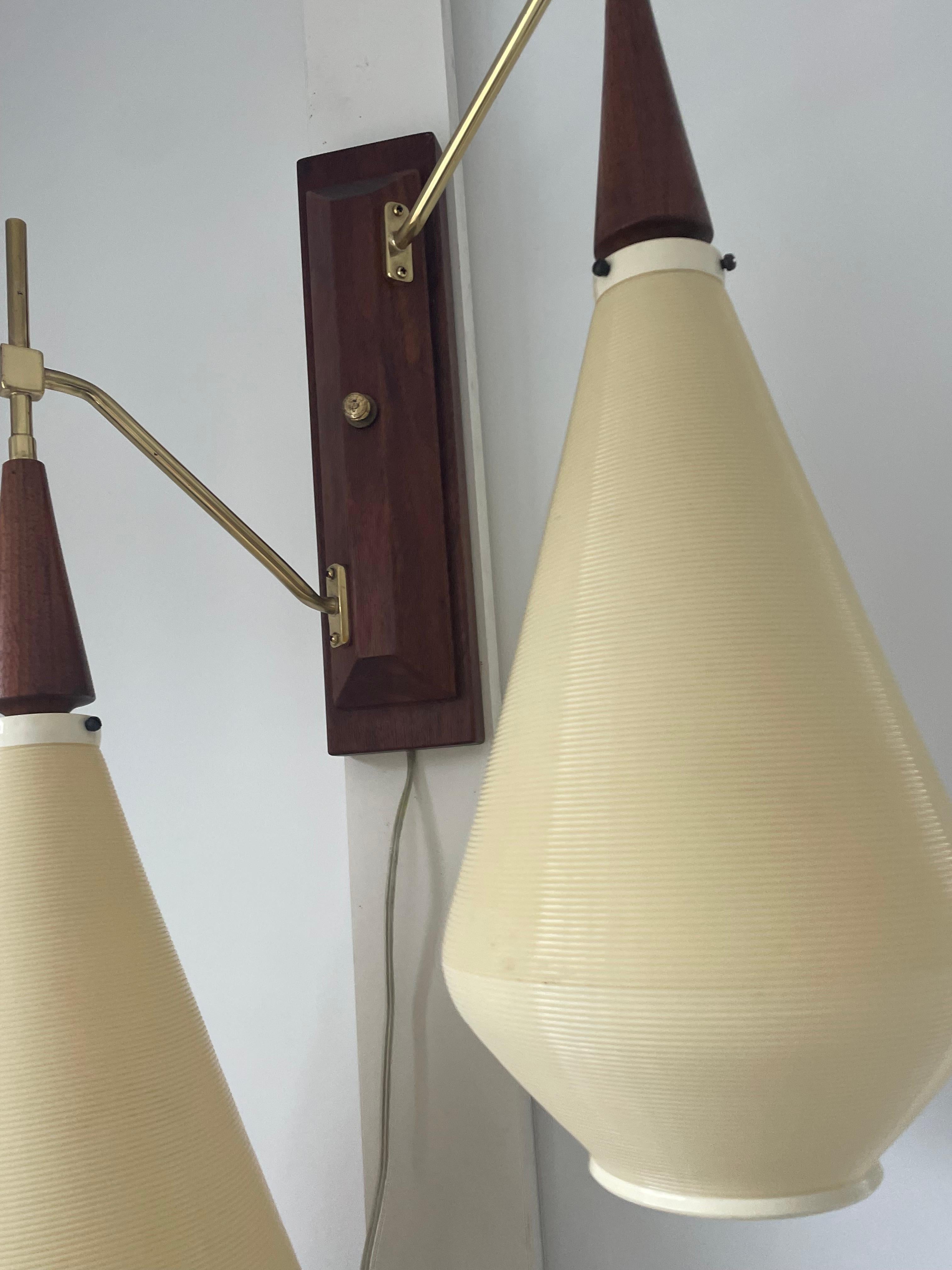 Rare and beautiful rotaflex wall lamp or sconce designed by Yasha Heifetz, The rotaflex teardrop shades are cream colored and made of a ribbed spun cellulose acetate. The arms are brass with teak trim and a teak wall mount. The fixture emits a