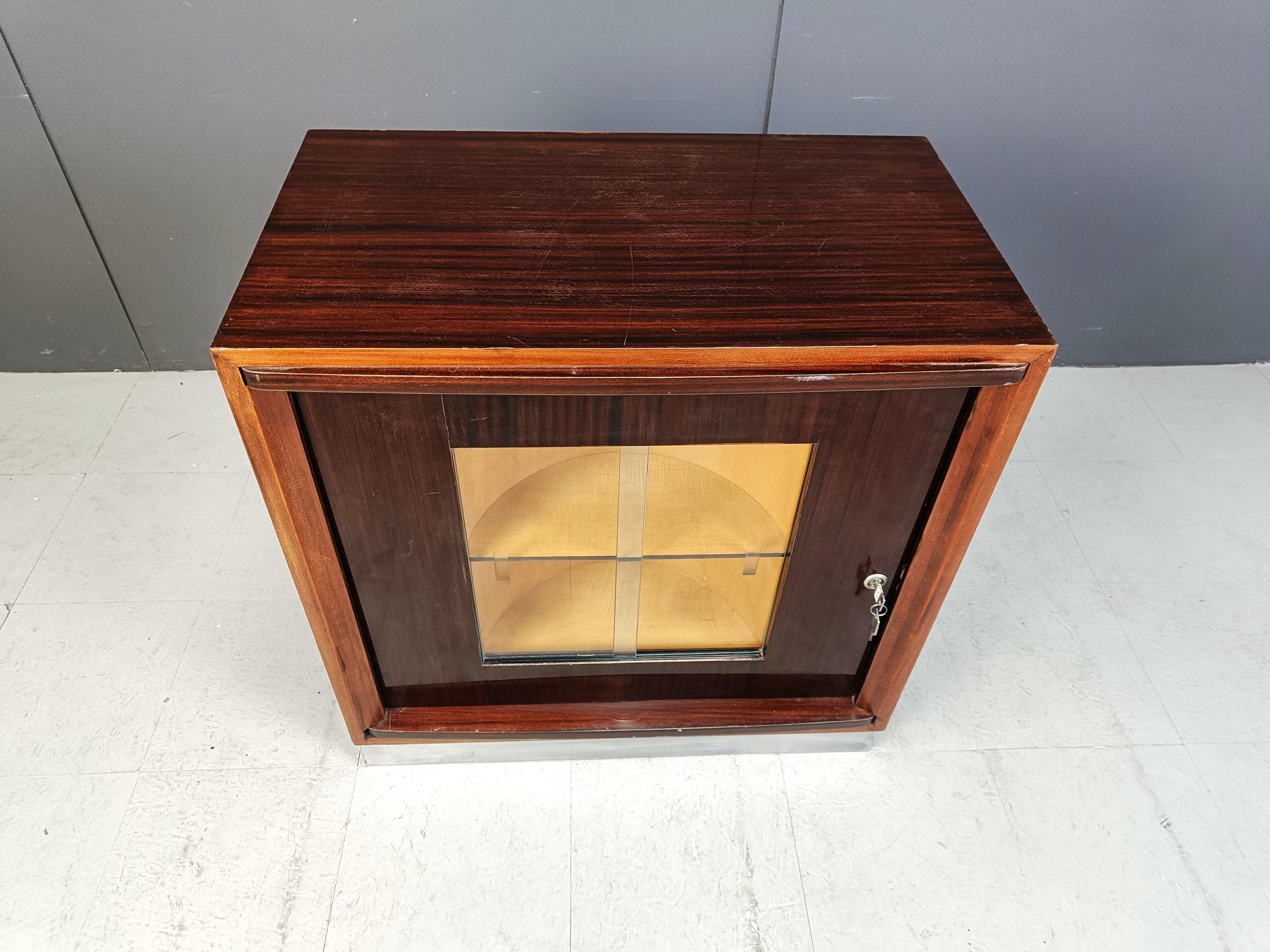 Mid century rotating bar cabinet from the 1960s.

The front glass panels can slide open to store glasses,...

With a twist of the key you can unlock the cabinet and rotate the inner part of the cabinet to reveal a bottle storage space.

Beautiful