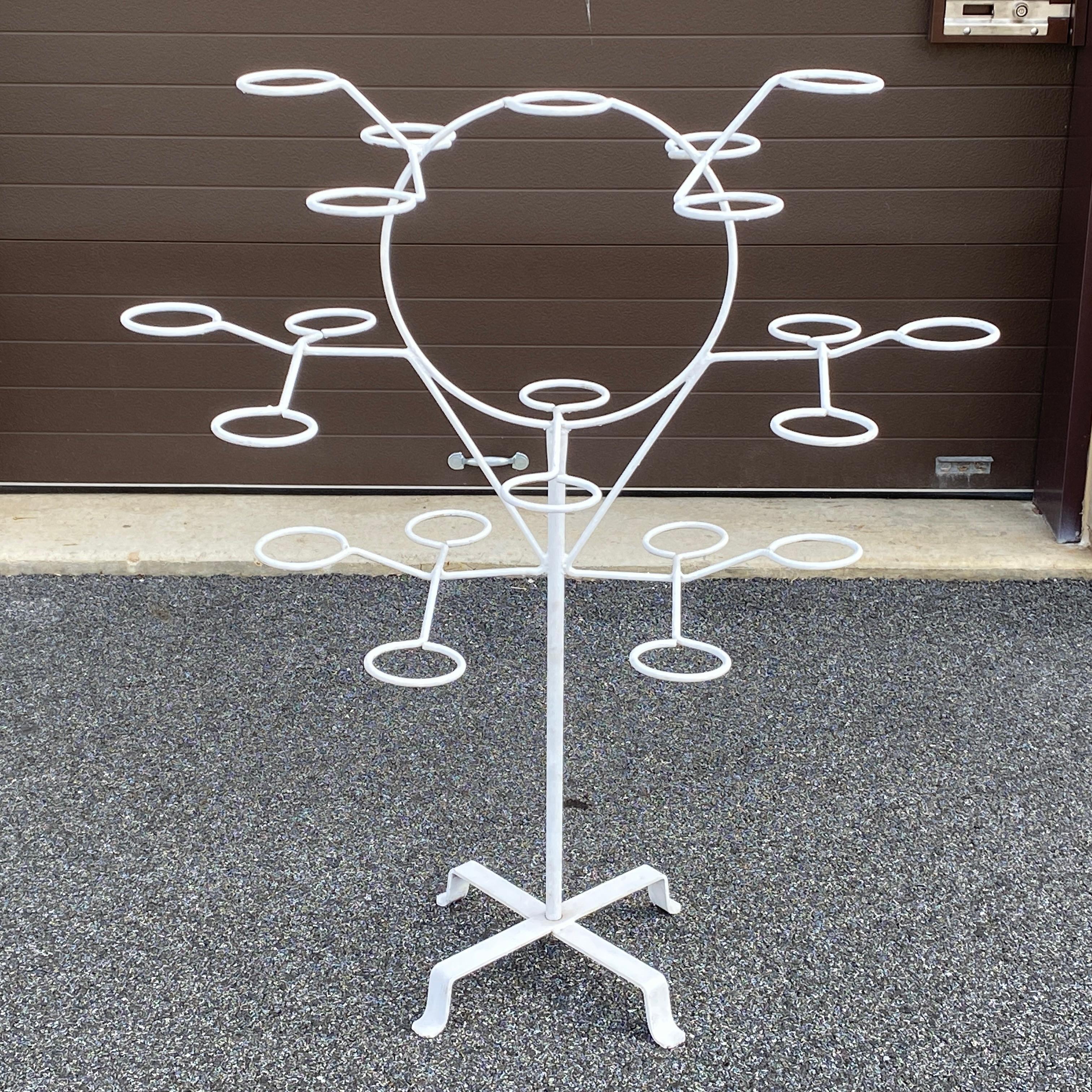 A rare mid-century rotating wrought iron plant stand of 21 pot rings each with an inside diameter of 4