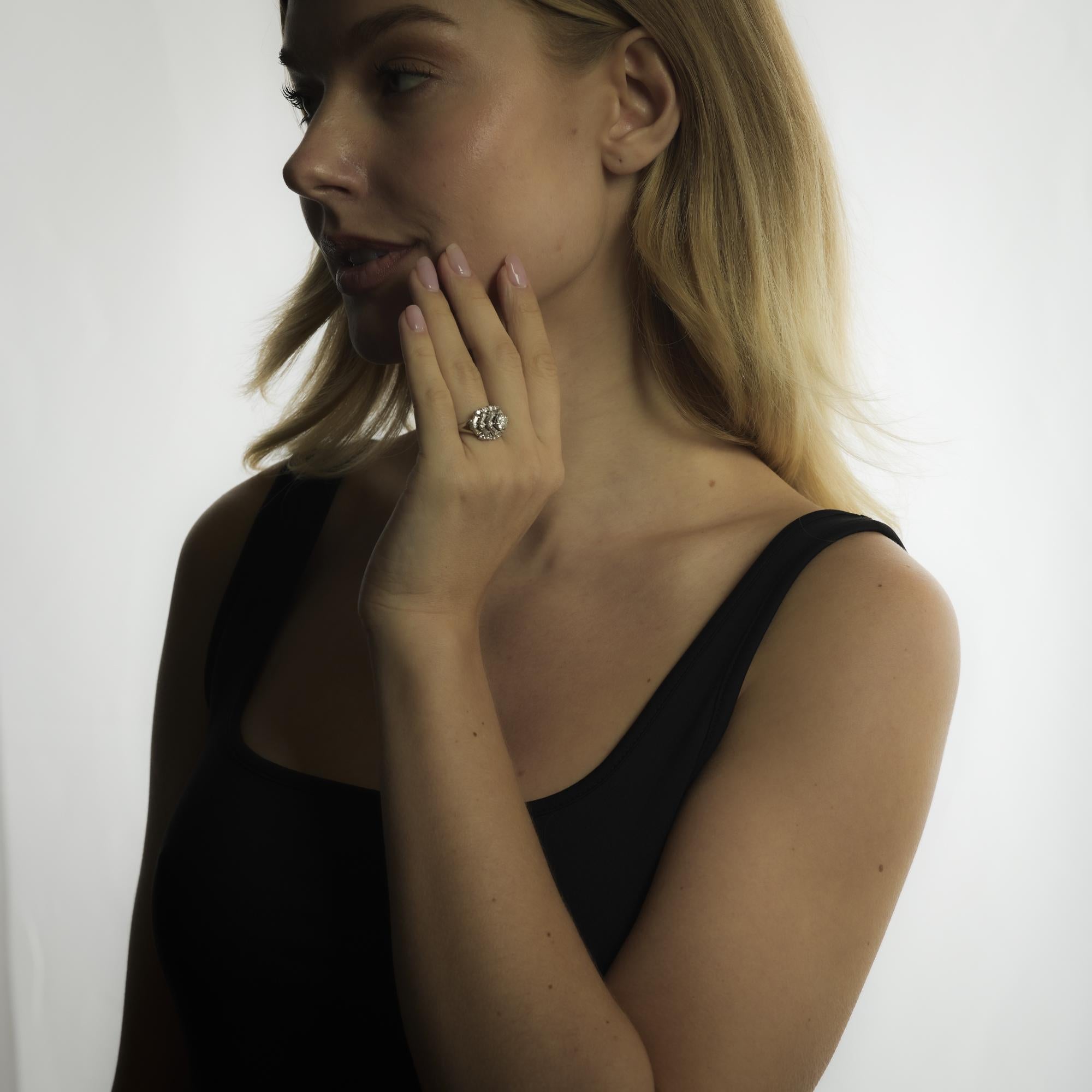 This Mid Century platinum ring showcases an old European cut diamond of approximately 0.80 carats, framed by tapered baguette and round brilliant diamonds totaling 1.30 carats for refined elegance.