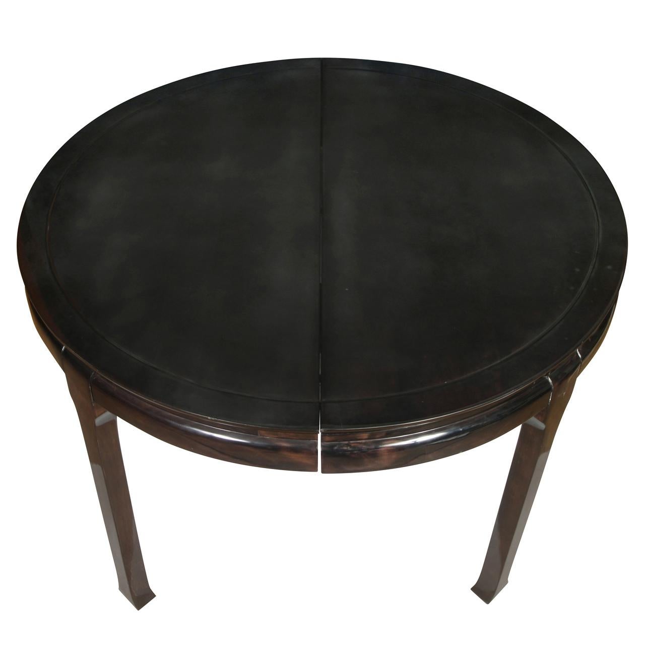 A Mid century Asian style round dining table with one leaf, lacquered black - brown finish. Includes one leaf, measures 20