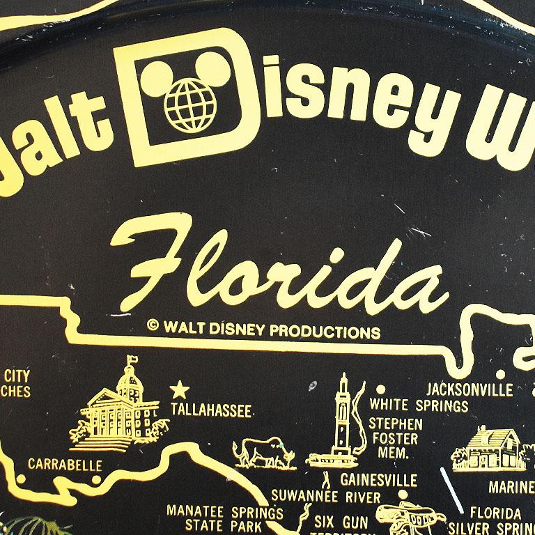 A Mid-Century Modern round black tin serving tray. This serving tray will be an excellent addition to any bar. The inside is printed with Walt Disney World in Florida with its towns and attractions. Several Disney characters are placed throughout,
