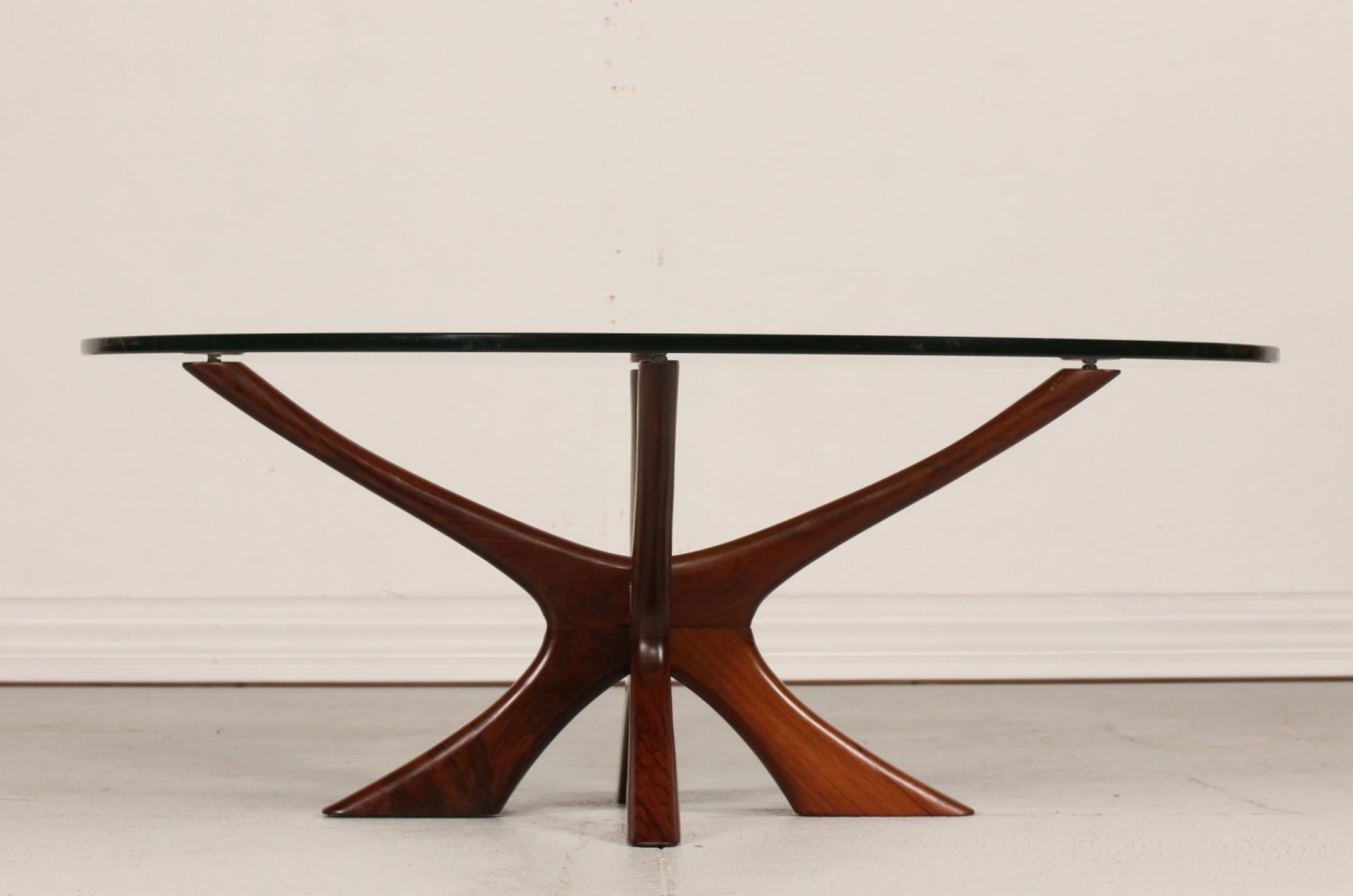 Scandinavian midcentury coffee table with round glass top on a sculptural solid wood frame.
Presumably made by Swedish Örebro Glasindustri AB.
The table is attributed to Fredrik Schriever-Abeln or the Danish architect Illum Wikkelsø.
