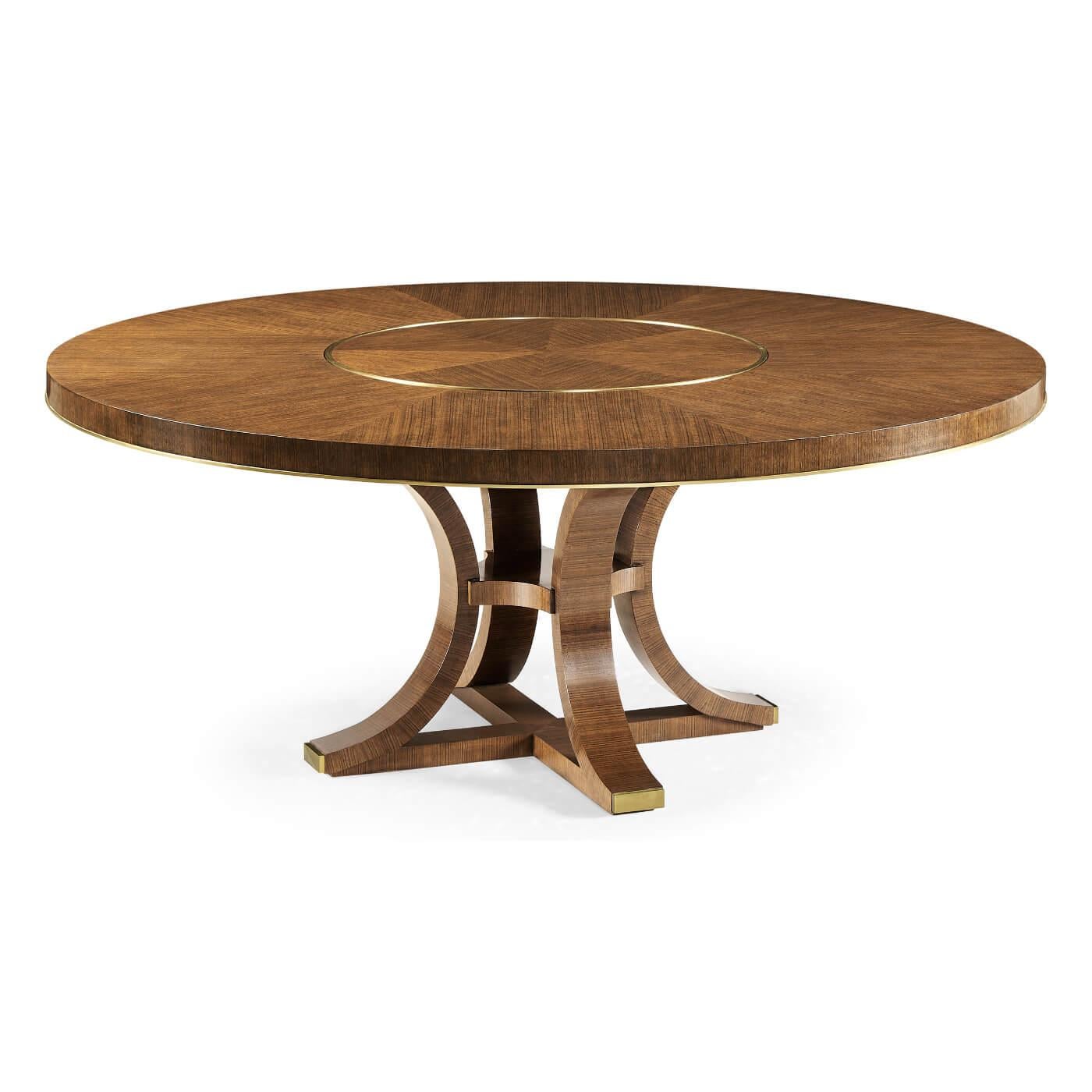 A midcentury style round dining table with in-built lazy Susan, veneered in a decorative hyedua with a raised brass inlay detail, set on elegantly curved supports terminating in brass caps.

Dimensions: 72