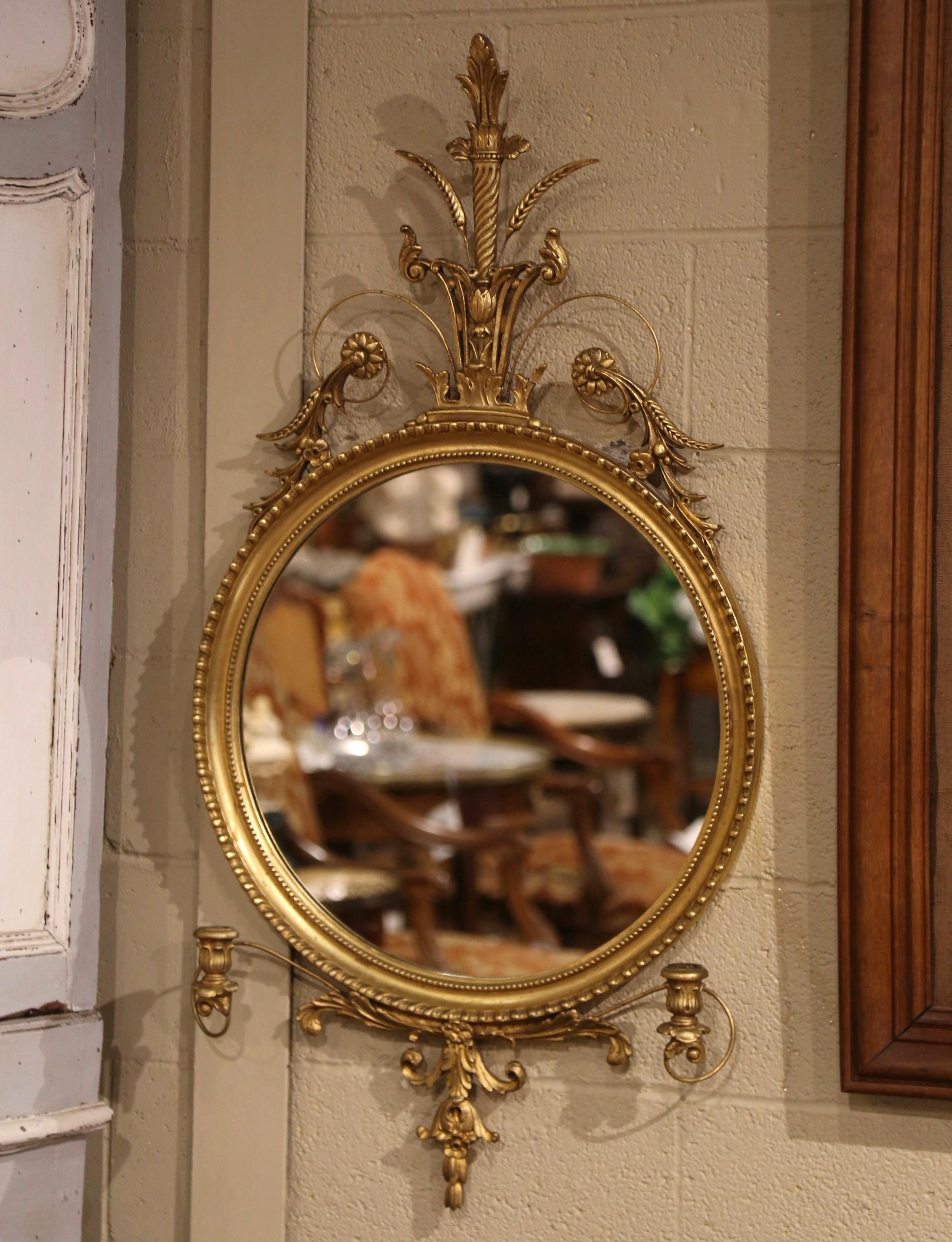 Decorate an entryway with this elegant vintage wall mirror. Crafted in Italy circa 1970 and round in shape the mirror is set within a hand carved, molded giltwood frame. At its peak is an intricately pierced centered crest composition of a fabulous