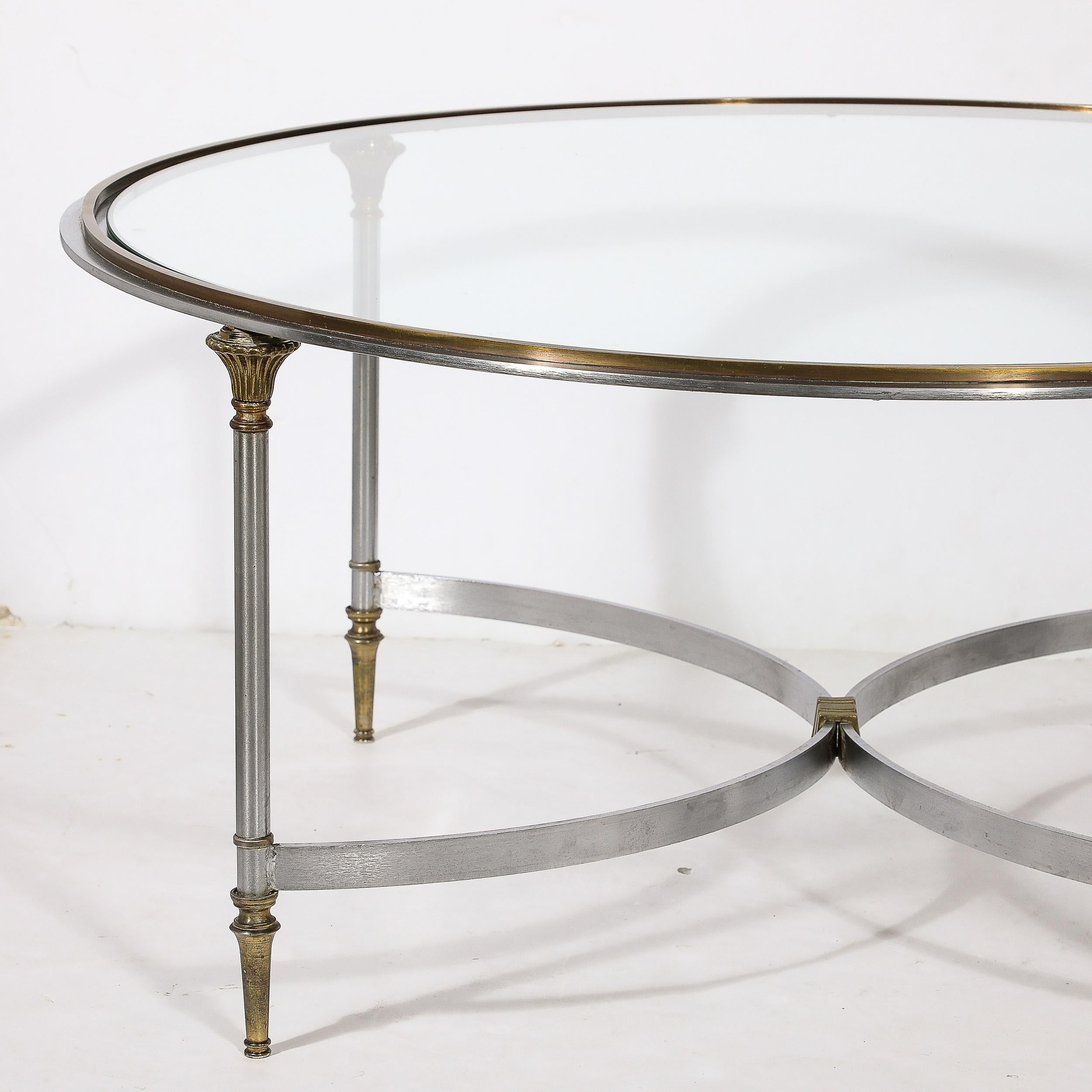 This sleek and linear Mid-Century Modernist Round Glass Top Brass and Steel Cocktail Table is in the manner of Maison Jansen and originates from Italy, Circa 1960. Features a banded composition in Brass and Steel, boldly combining the hues of each