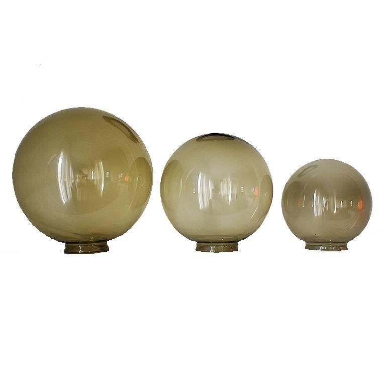 Three glass orbs sold as a set. Makes a gorgeous statement piece for a coffee table, dining table or credenza. Each very in size and feature a beautiful green/brown hue. 

Sizing for each of the globes are the following:
Large: 11