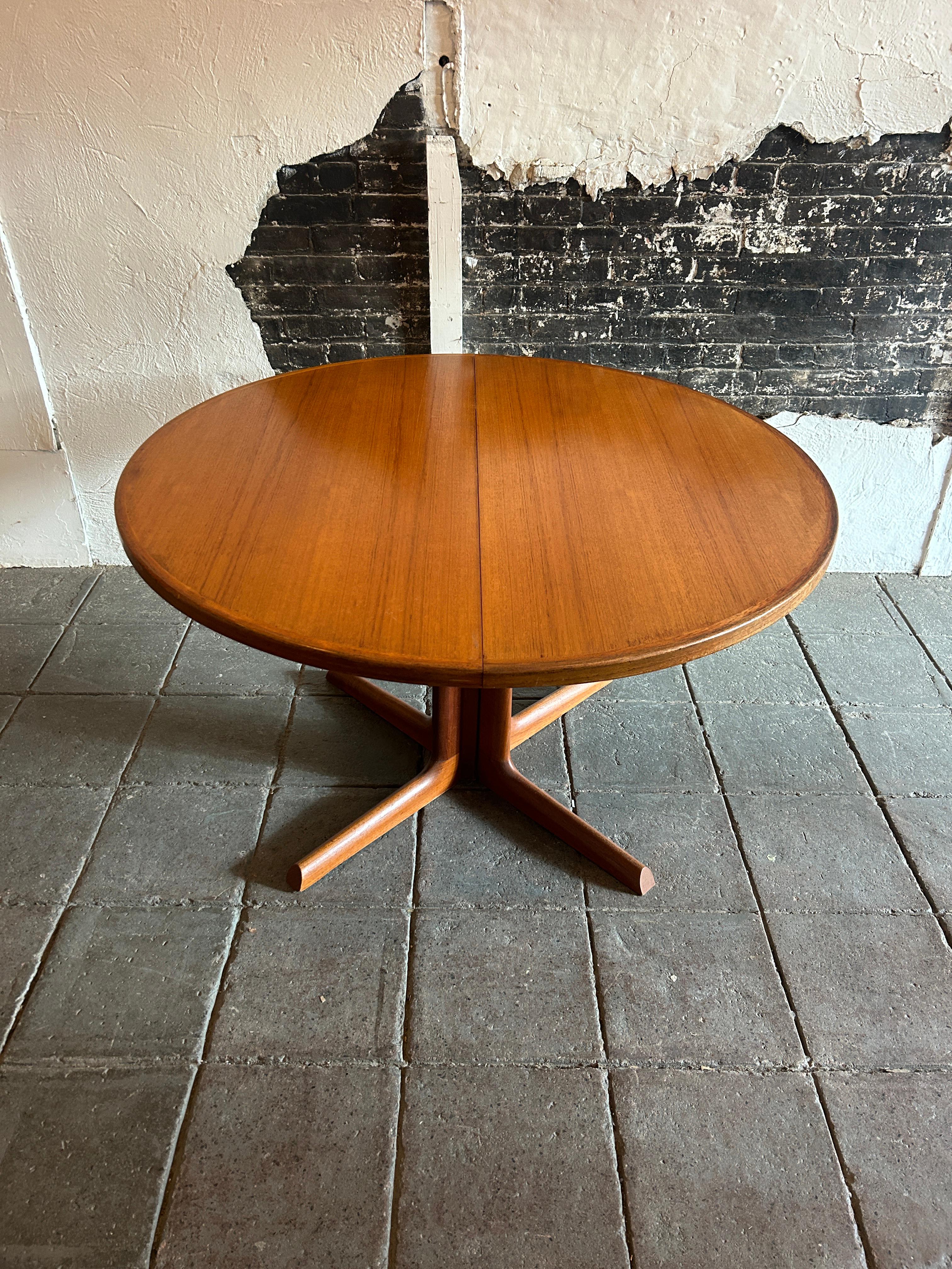 Stunning mid century Teak Round Danish Modern extension dining table with (2) leaves. This table has beautiful Teak Veneer top with Solid Teak ends and legs. This table is in beautiful condition with light golden brown black teak wood tones very