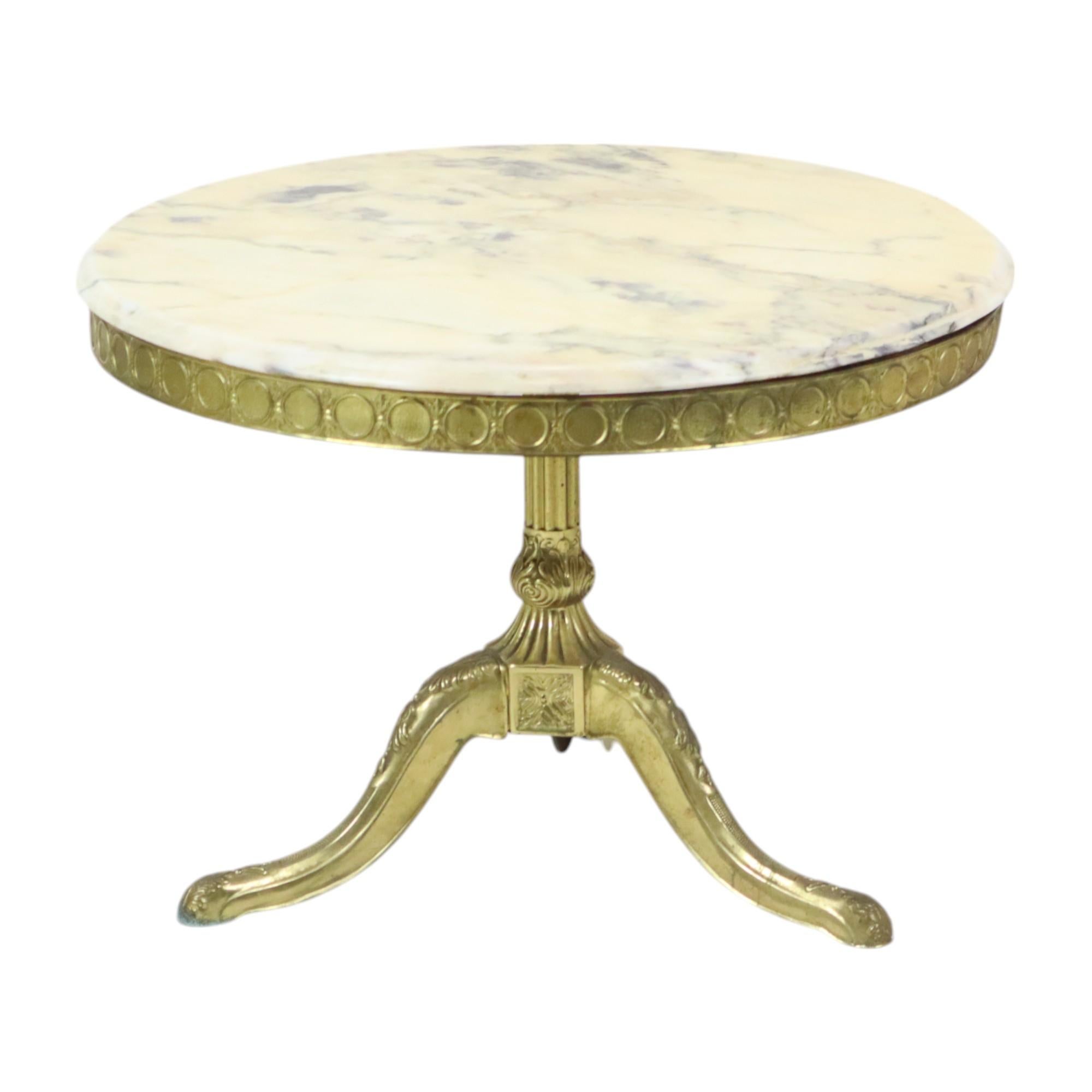 Mid century round coffee table, side table with round marble top and solid brass base, Hollywood Regency style from around the 50s.

Luxurious table of high quality, the brass base is extensively decorated with acanthus and patterns, the central leg