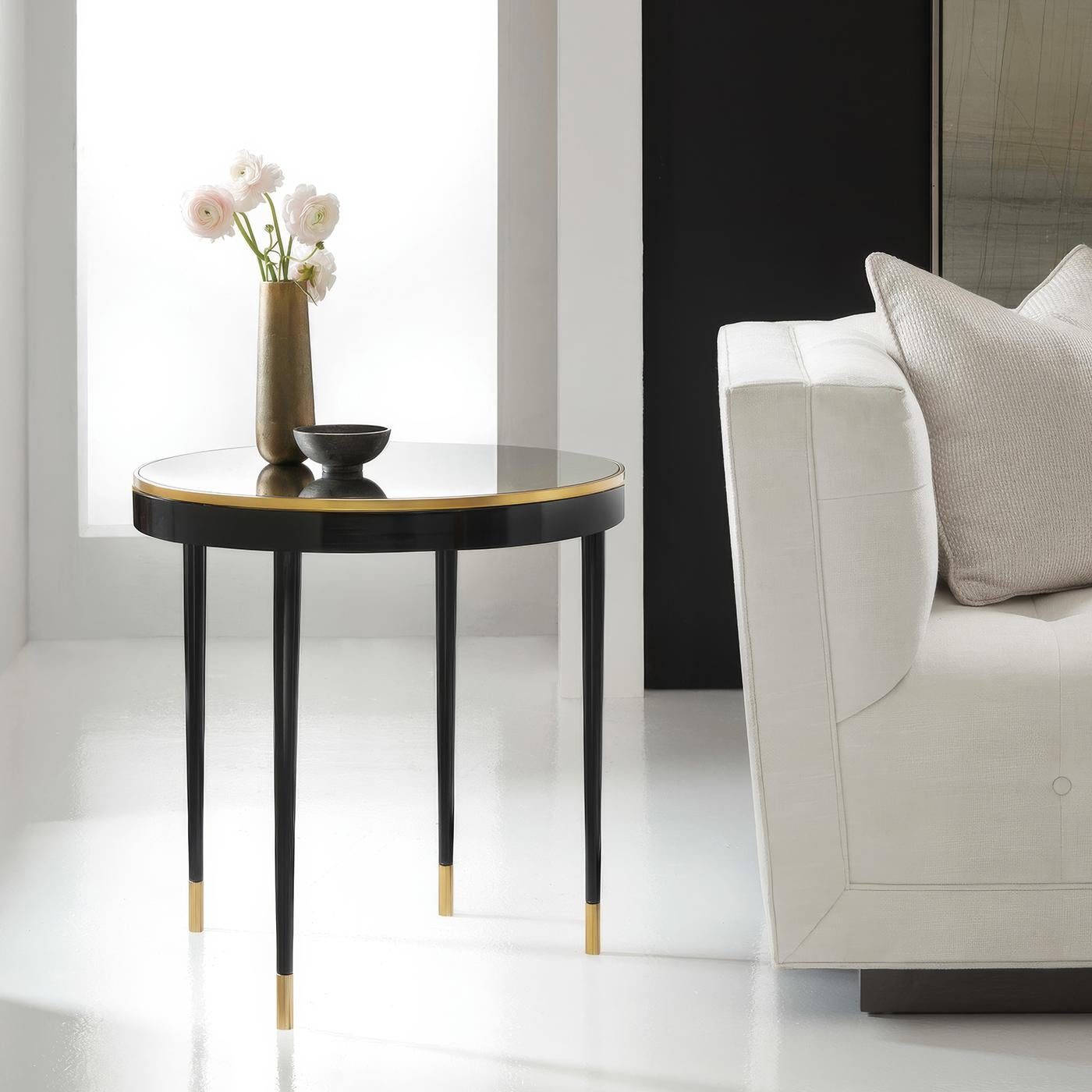 Une table d'appoint sophistiquée capture l'essence du design du milieu du siècle grâce à sa silhouette architecturale et à ses combinaisons de matériaux raffinés. Le plateau circulaire en miroir vieilli est élégamment encadré par une fine bande de