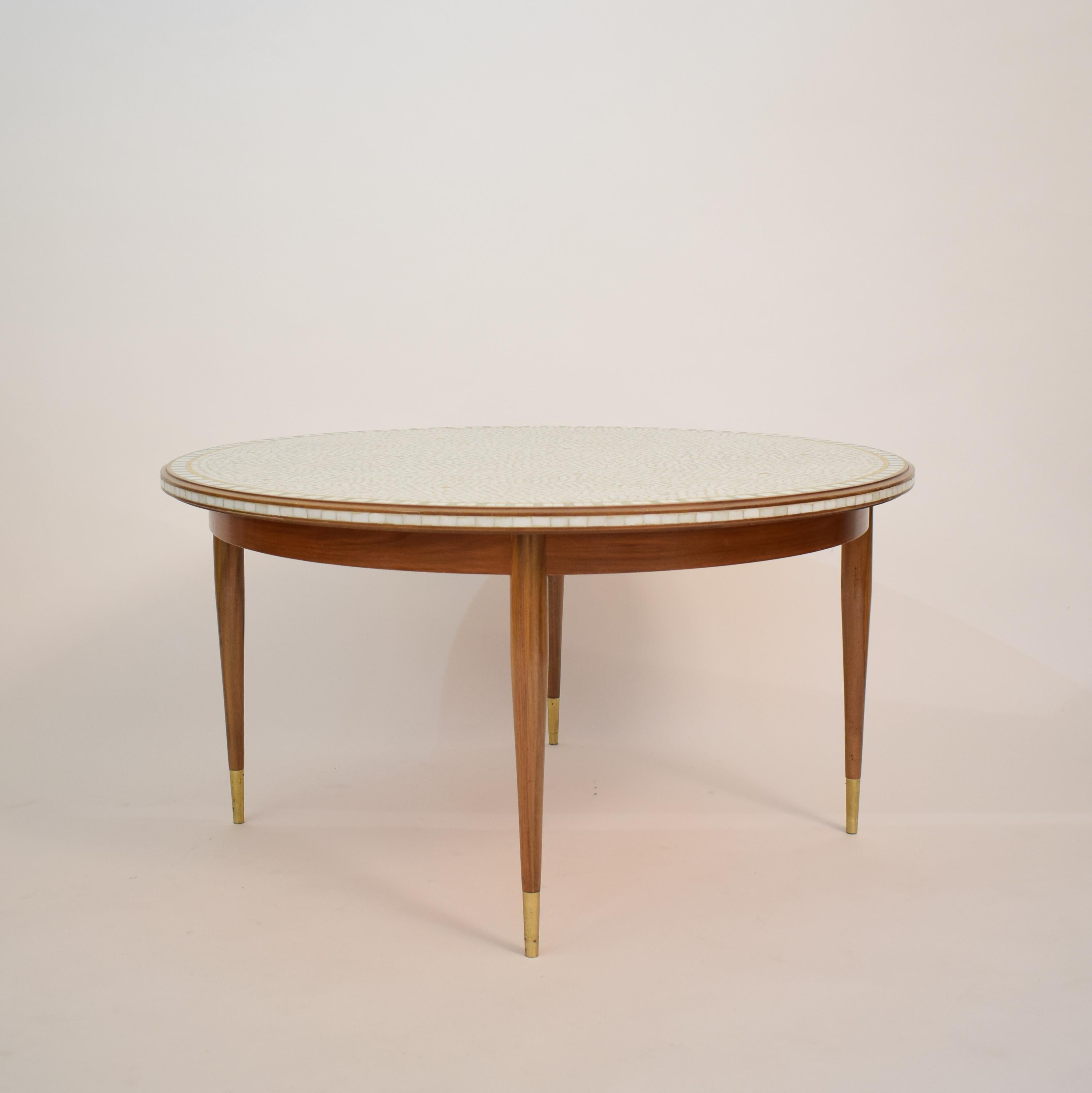 This beautiful and elegant round mosaic top coffee table with a Walnut frame and legs was designed by the German artist and sculptor Berthold Muller (1893-1979). 
The top has white ceramic stones combined with a gold and some mint green ceramic