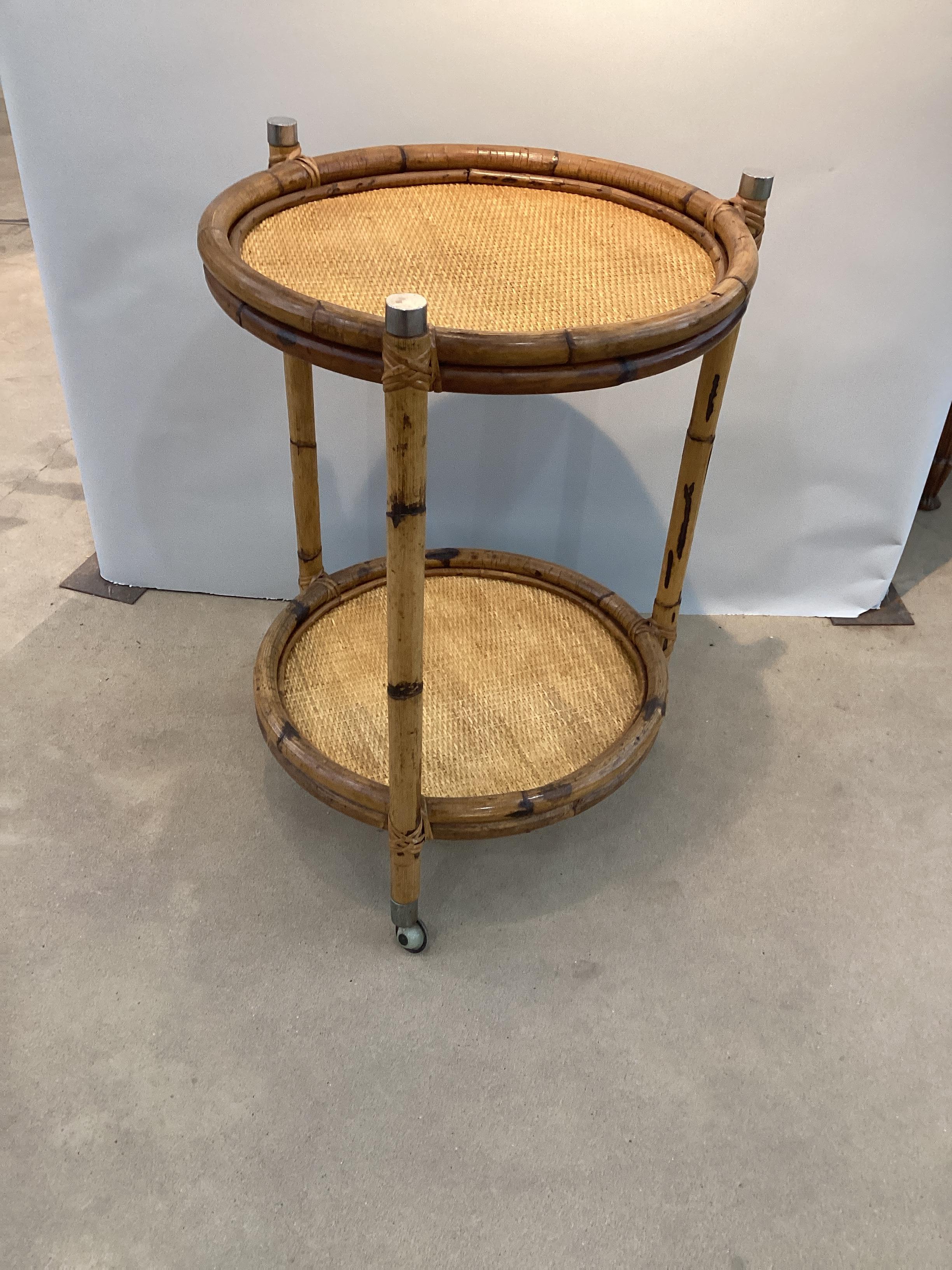 Chariot de bar en rotin rond du milieu du siècle. Les colonnes rondes en rotin sont surmontées d'un capuchon chromé. Les étagères sont toutes deux dotées d'un plateau en rotin pressé. Le chariot se déplace librement. Une belle addition à un