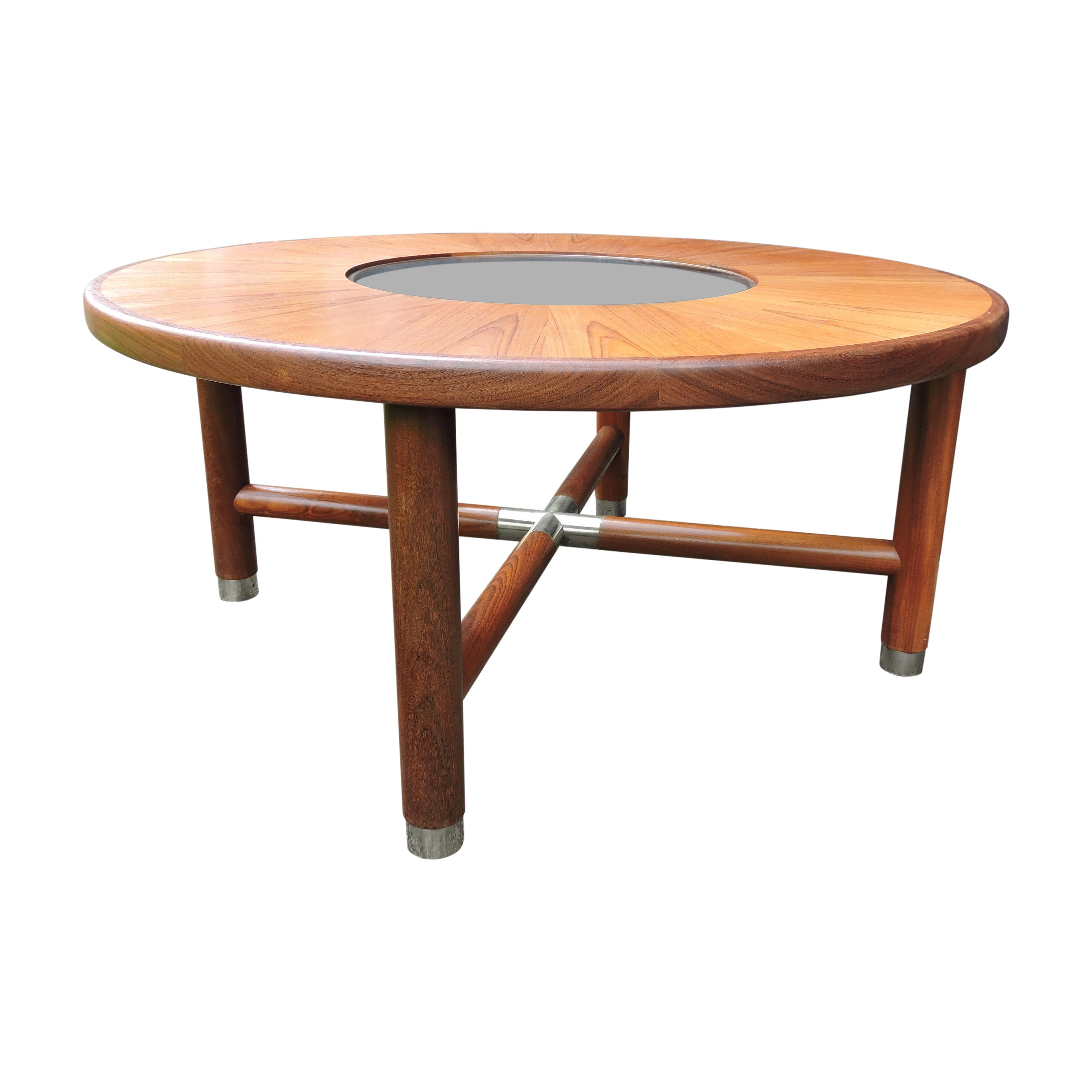 A 1960s round teak and glass coffee table by G-Plan featuring brass ended legs and centre cross.
