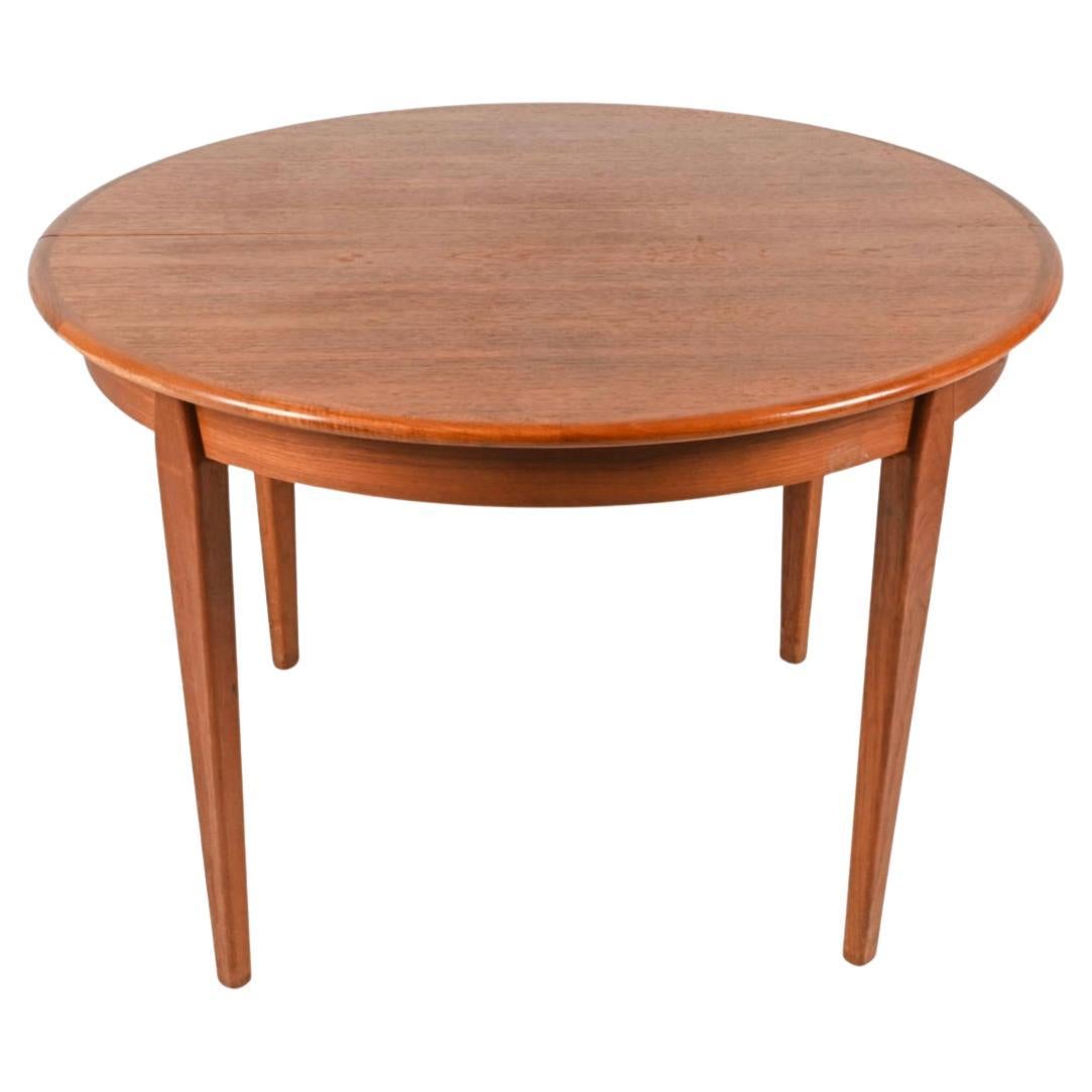Mid century Teak Round Danish Modern extension dining table with (2) leaves. This table has Solid teak wood legs. This table is in beautiful condition with medium brown black and tan teak tones. Great construction and both leaves match the tables