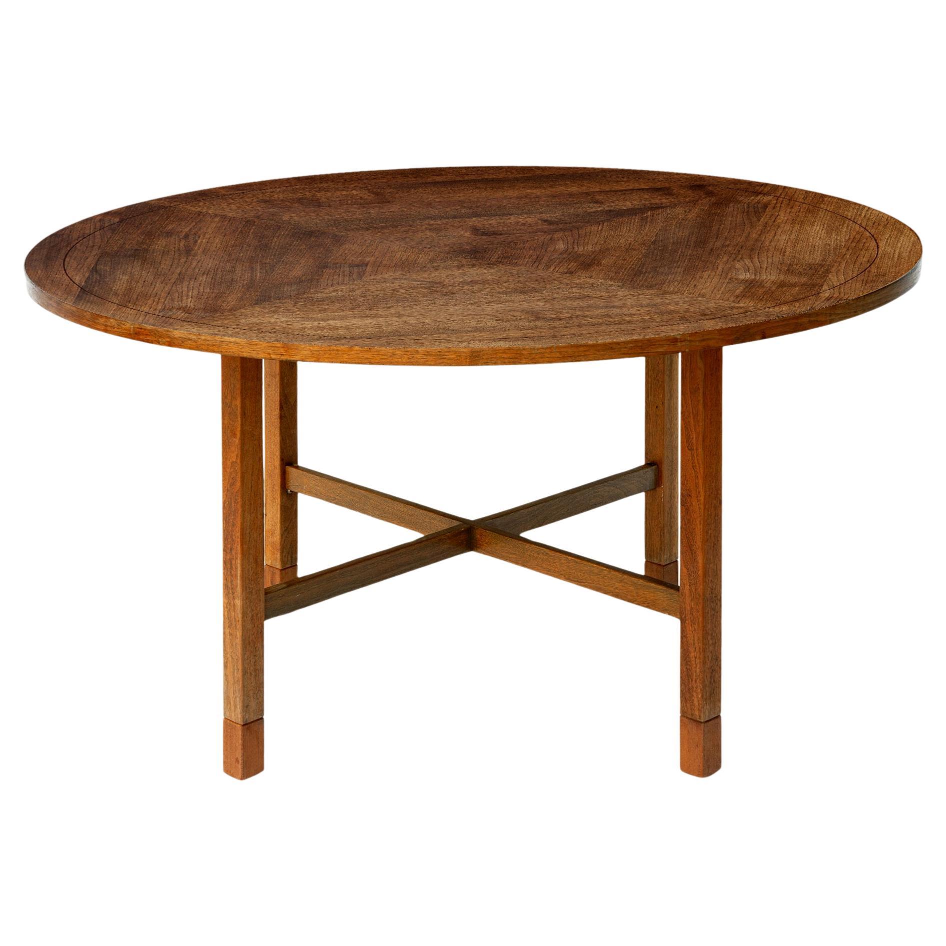 Danish Modern Mid-Century round table which has segmented top with four panels in teak veneers. 
The legs are straight with cross bar stretchers.