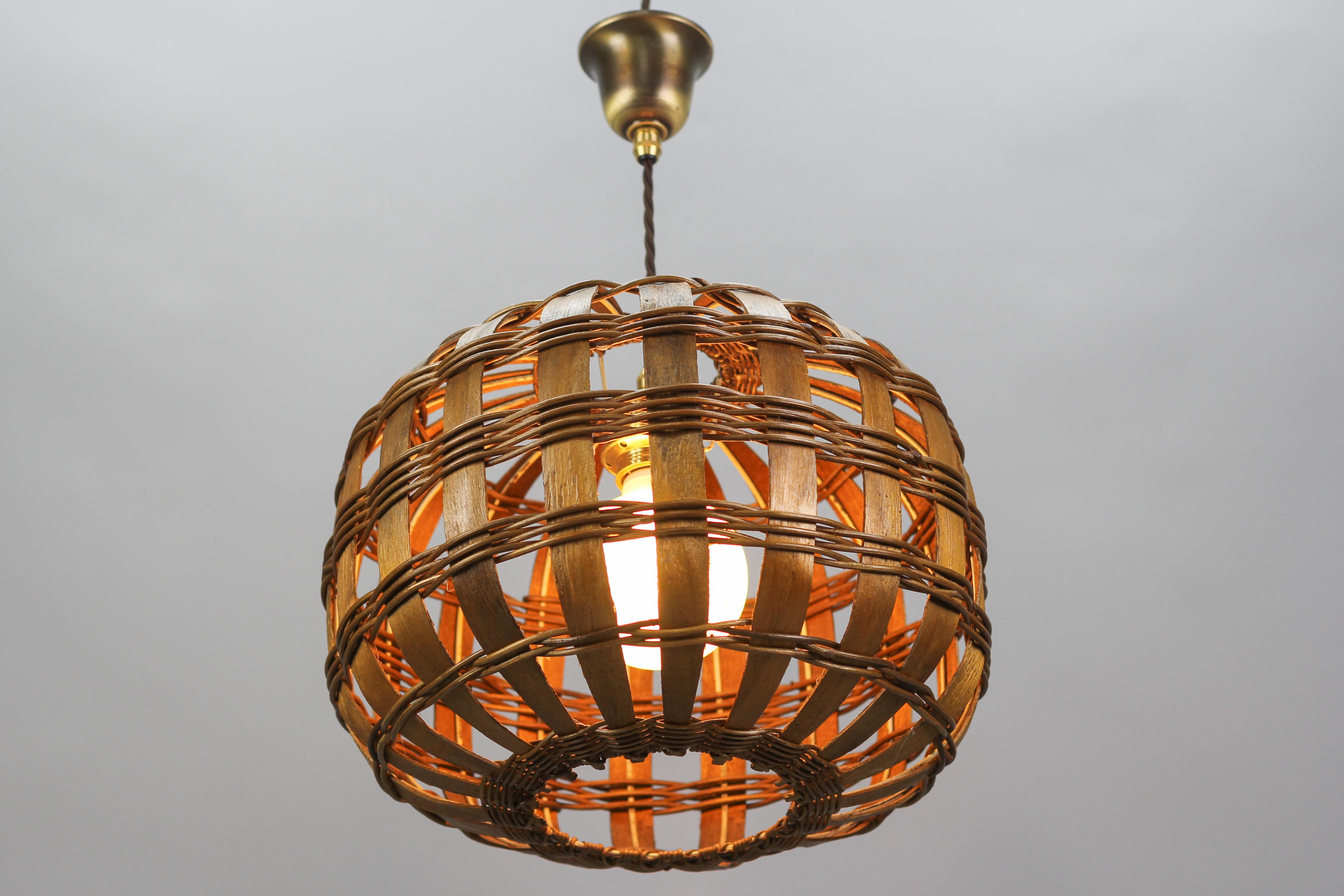 Amazing woven wood pendant light fixture with metal frame and brass canopy.
This beautiful Mid-century period round pendant lamp is height adjustable and the natural color of the wood creates a warm and diffused light. 
One socket for E27 (E26) size
