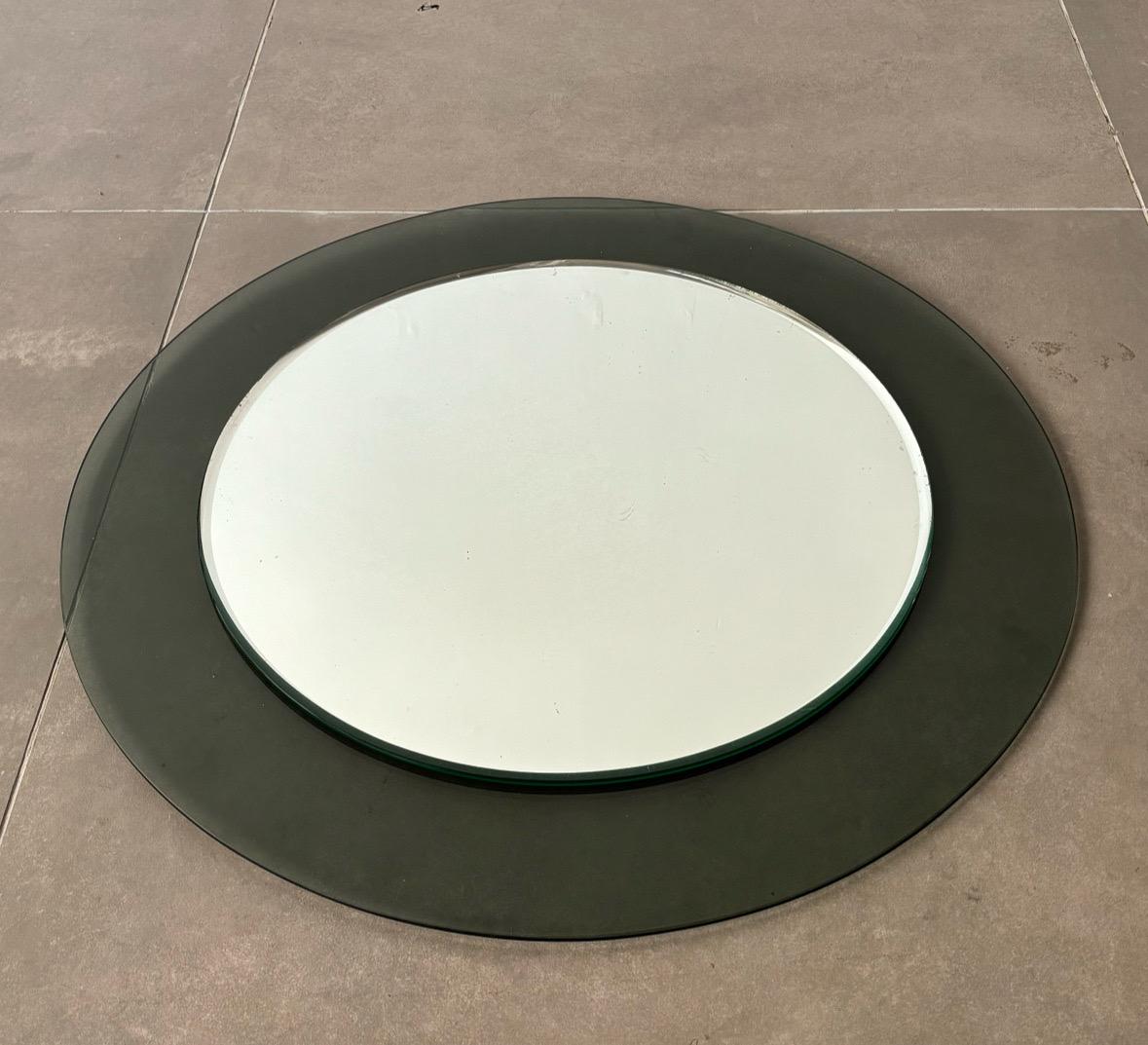 Ce miroir arrondi du milieu du siècle de Veca, fabriqué en Italie dans les années 1970, témoigne de la maîtrise de la marque en matière d'élégance minimaliste. D'un diamètre de 70 cm, le miroir présente un design circulaire encadré de verre teinté