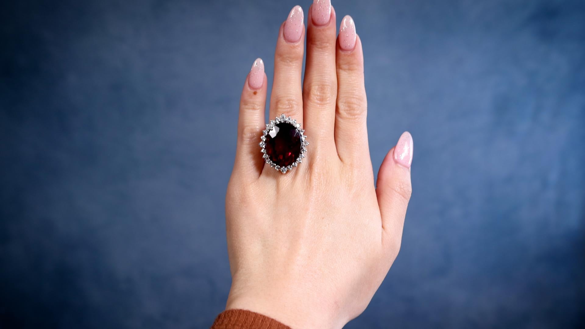 One Mid-Century Rubellite and Diamond Platinum Cocktail Ring. Featuring one oval brilliant cut rubellite weighing 19.30 carats. Accented by 24 round brilliant cut diamonds with a total weight of approximately 0.60 carat, graded near-colorless, SI