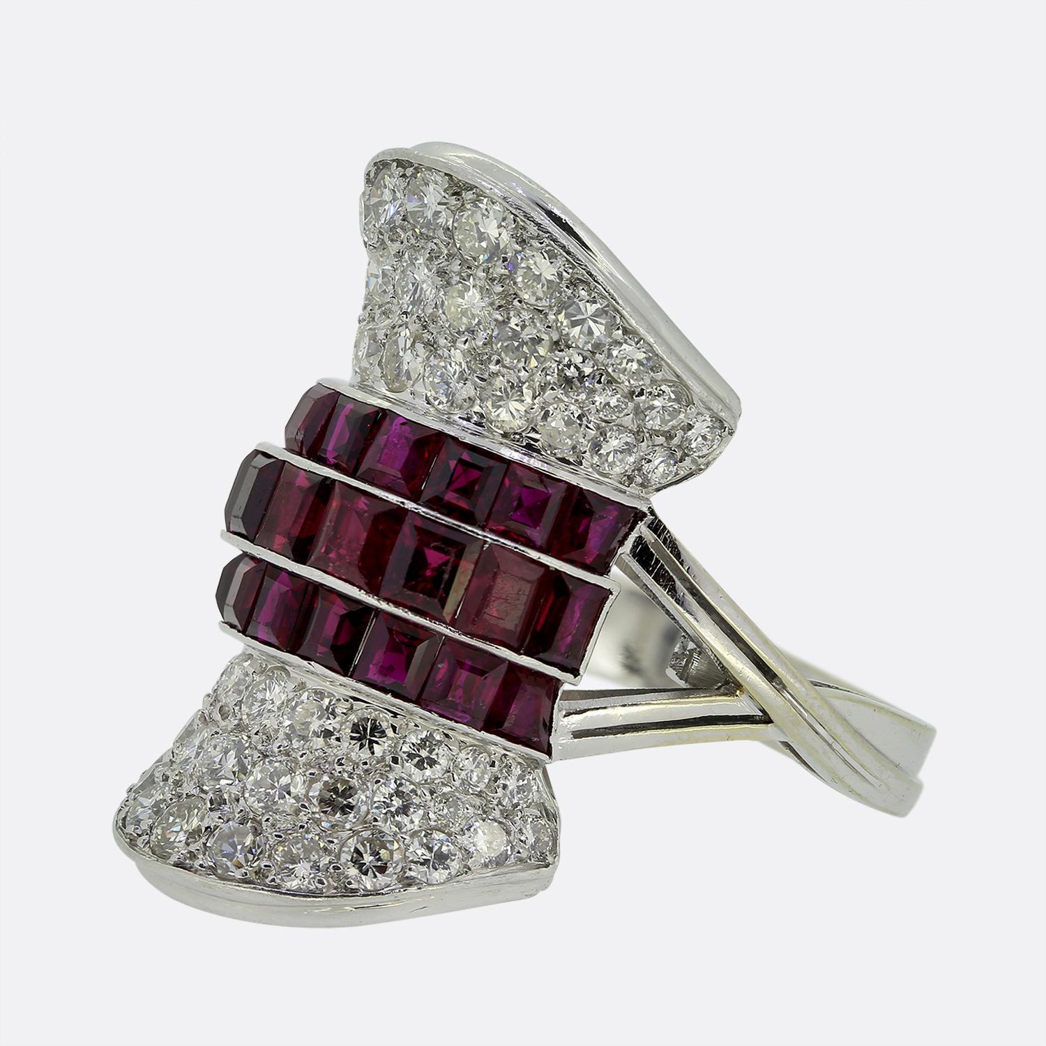Here we have striking dress ring showcasing a bold design with square-cut red rubies as the central feature. These vibrant stones are flanked by a backdrop filled with bright white round brilliant-cut diamonds, creating a stunning contrast. The ring