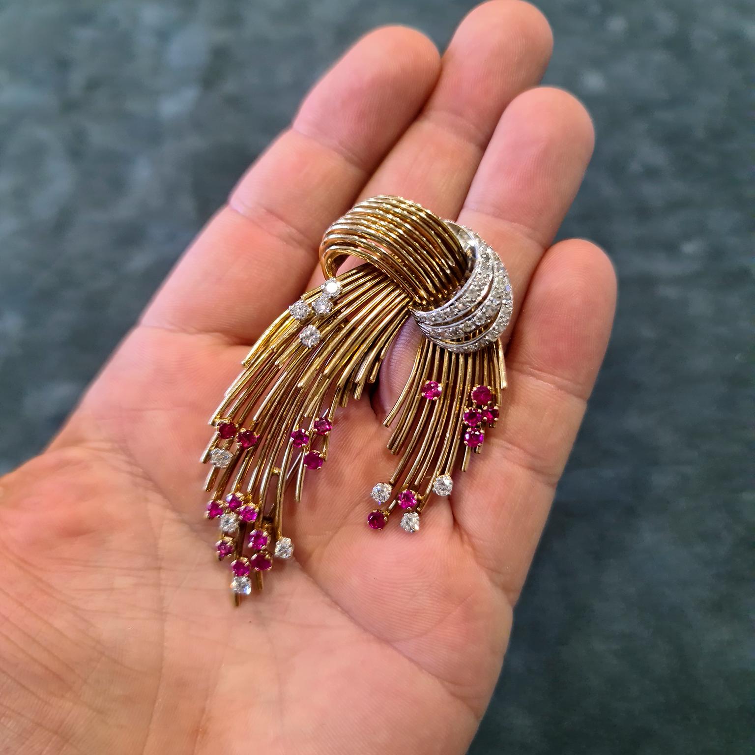 A stylish and impressive brooch, instantly recognisable as Kutchinsky. Wires of 18-carat yellow gold formed in a spray fashion, mounted with blood-red rubies and diamonds. Hallmarked London. Total diamond carat weight of approximately 2.50 carats,