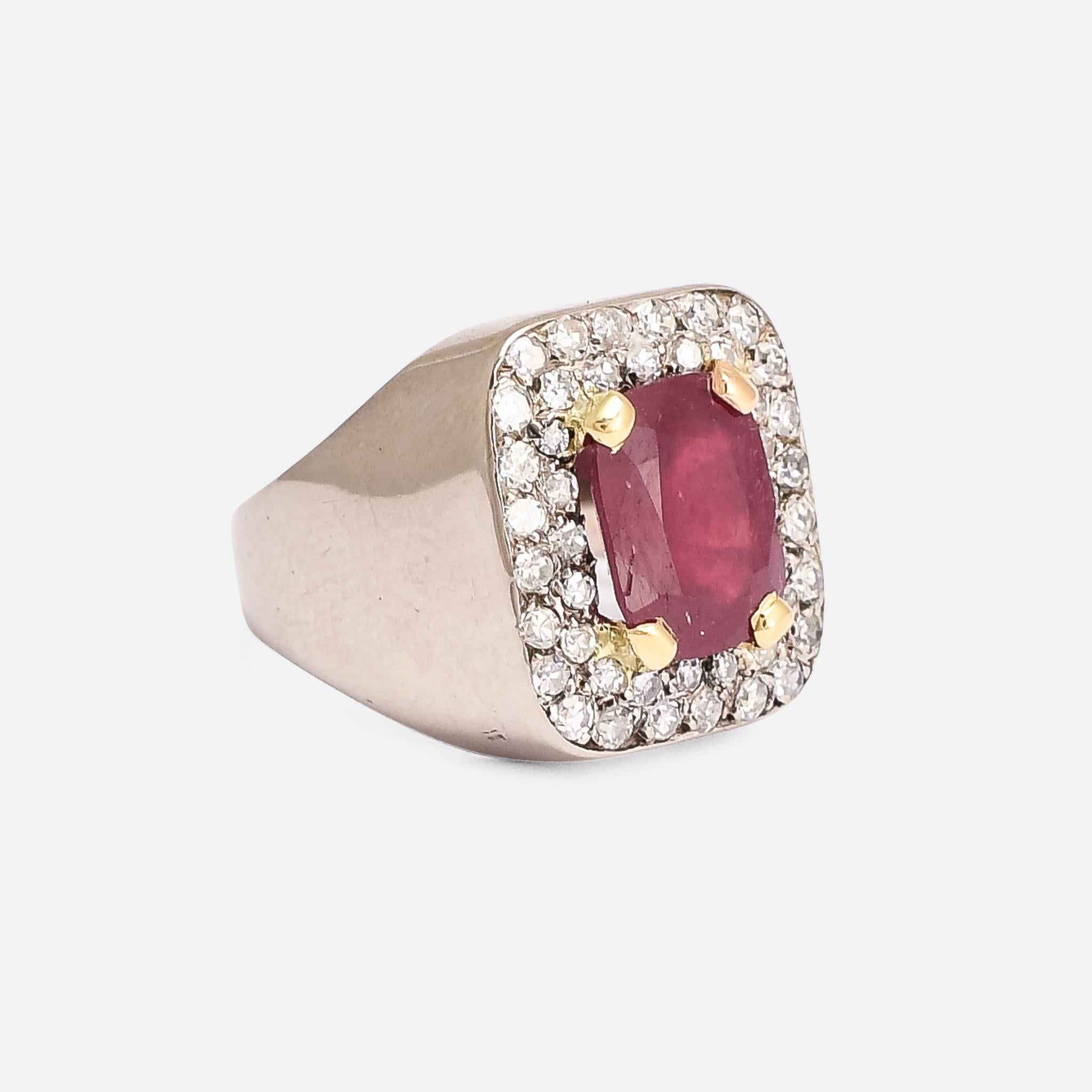 A cool vintage signet/pinky ring dating from the 1950s. It's set with a central 3.5 carat cushion cut ruby, within a pavé border of bright white diamonds. The ruby is secured by four yellow gold claws, creating a pleasing bi-metal contrast with the