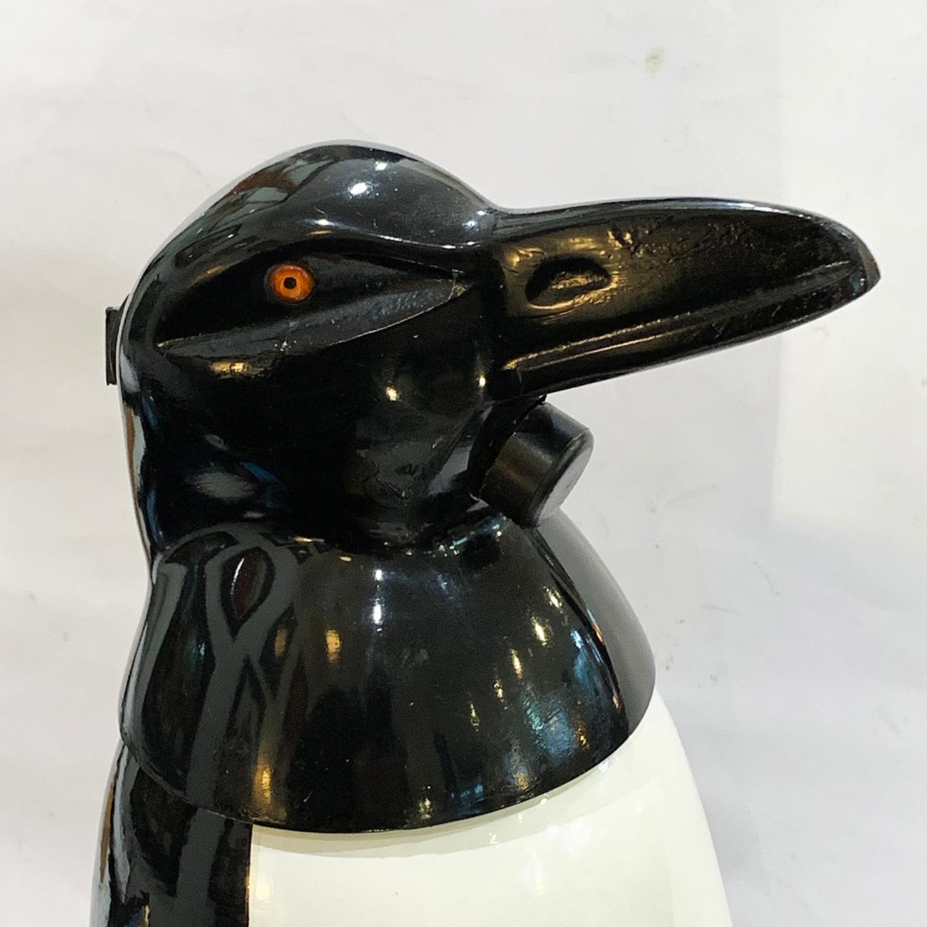 Art Deco Russian penguin soda syphon, in black and white enamel to the pressure welded cylinder, white Bakelite feet, glass eyes set to cast stainless steel head with black enamel. The throat has a button at, that when pressed, releases the soda