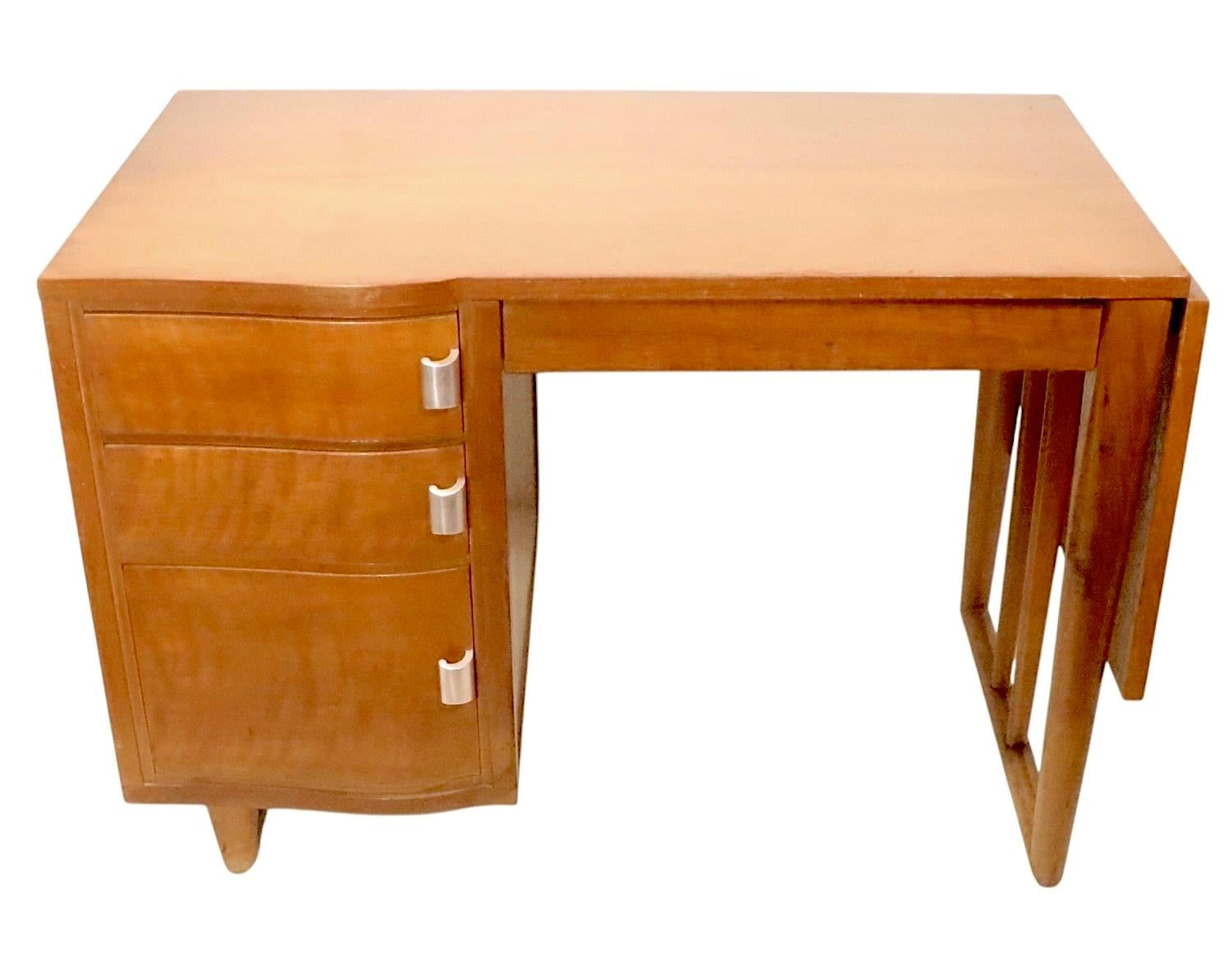 Chic mid century desk designed by Eero Saarinen for the John Stuart  Furniture Company, circa 1950's. This stylish desk features a rectangular top, with a drop side leaf, which can be raised to create a larger surface. 
 The desk has a bank of three