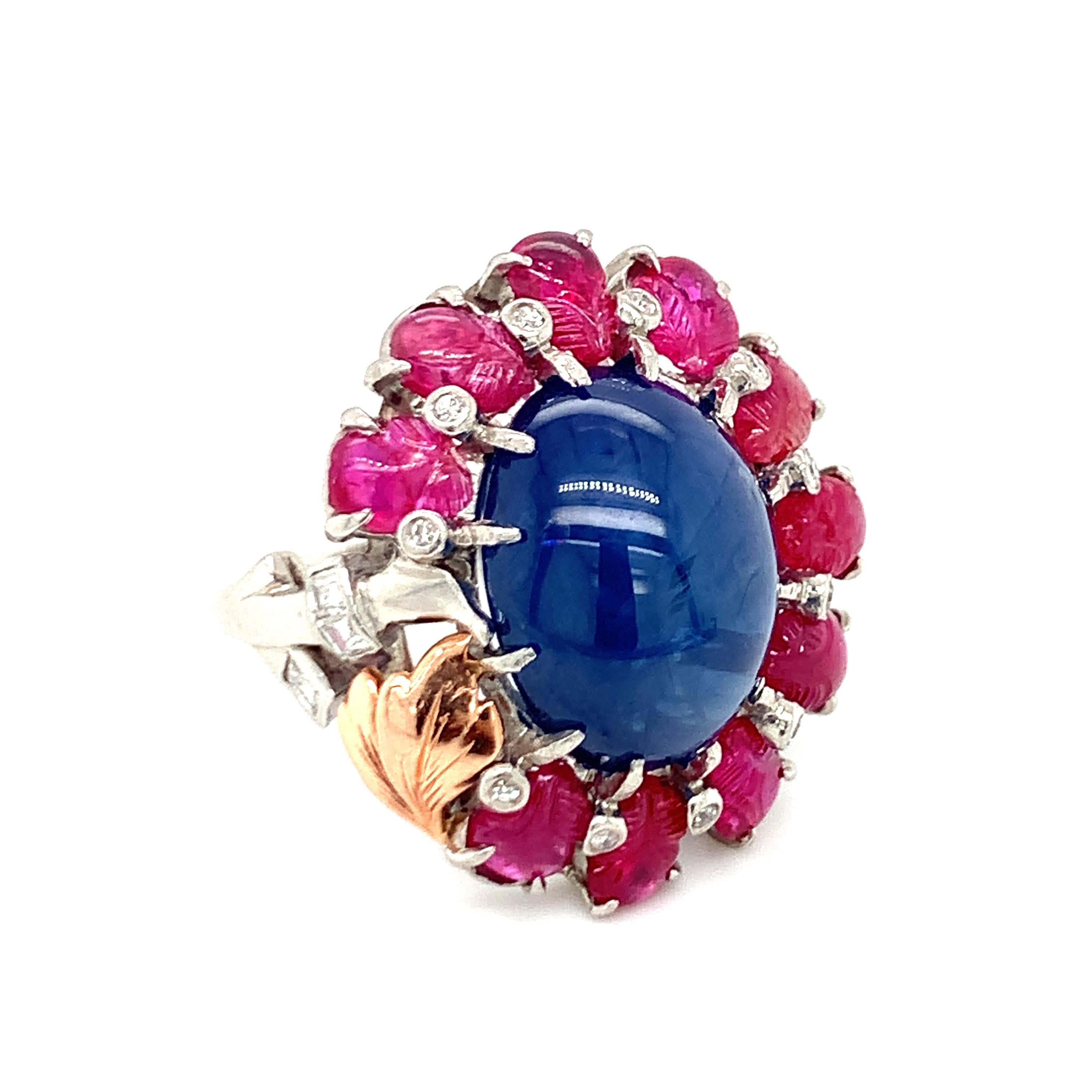 One mid-century sapphire, ruby and diamond platinum ring centering one oval cabochon sapphire weighing 18 ct. surrounded by ten carved cabochon rubies weighting 5 ct. Accented by a single rose gold leaf and 14 single round and square cut diamonds