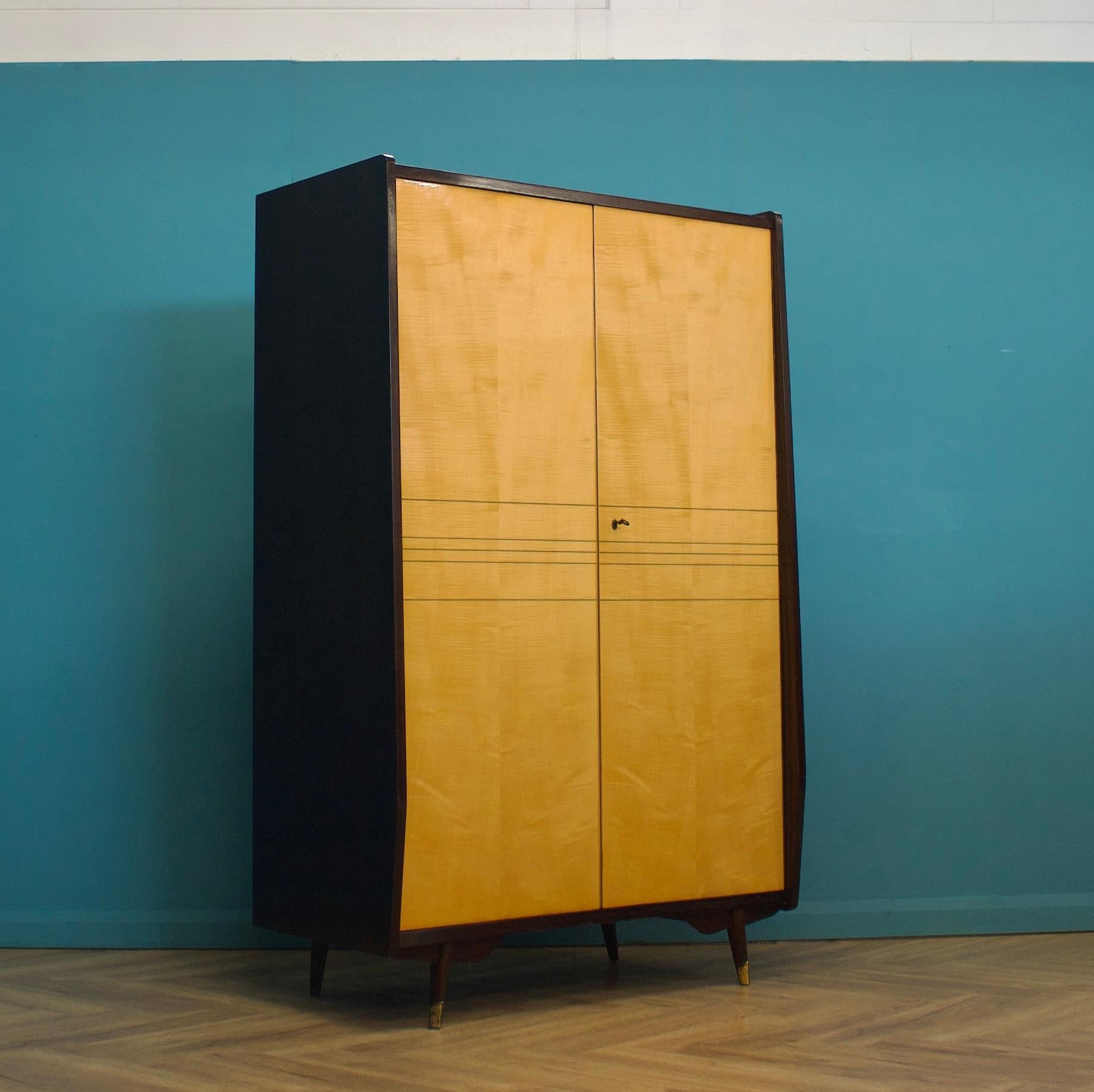 Une armoire en bouleau et noyer du milieu du siècle de Times Furnishings, dans le style italien, vers les années 1960.


Il présente une finition brillante sur les portes et des pieds évasés avec des détails en laiton. La serrure fonctionne et la
