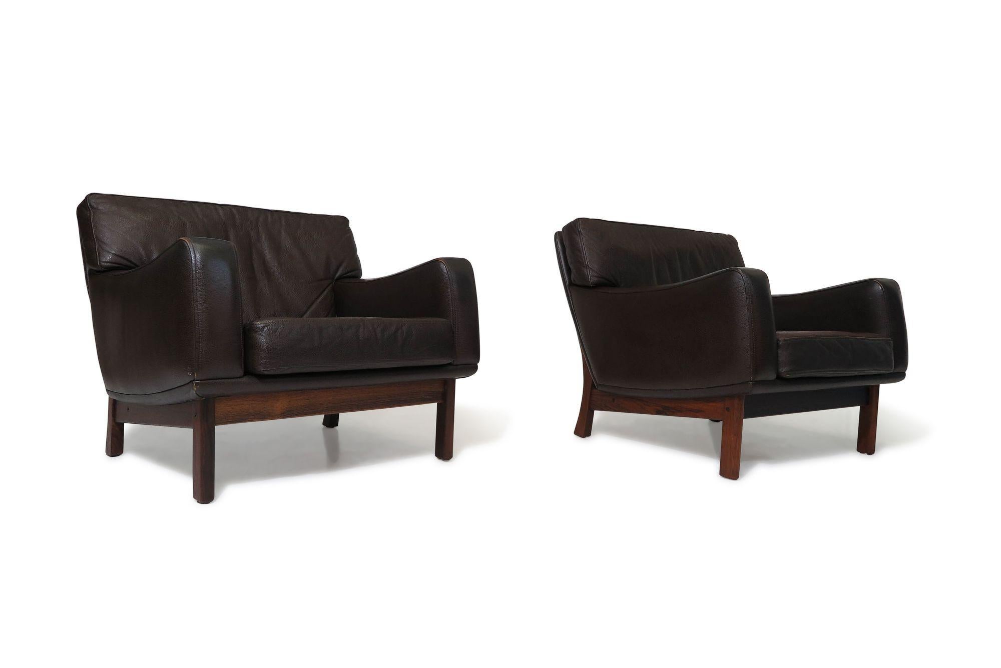 Hochwertige dänische Loungesessel mit Massivholzrahmen und Polsterung aus braunem Originalleder. Diese Stühle sind mit doppelt abgesteppten Kissen aus genarbtem Leder ausgestattet und stehen auf ausgestellten, geschwungenen Beinen aus