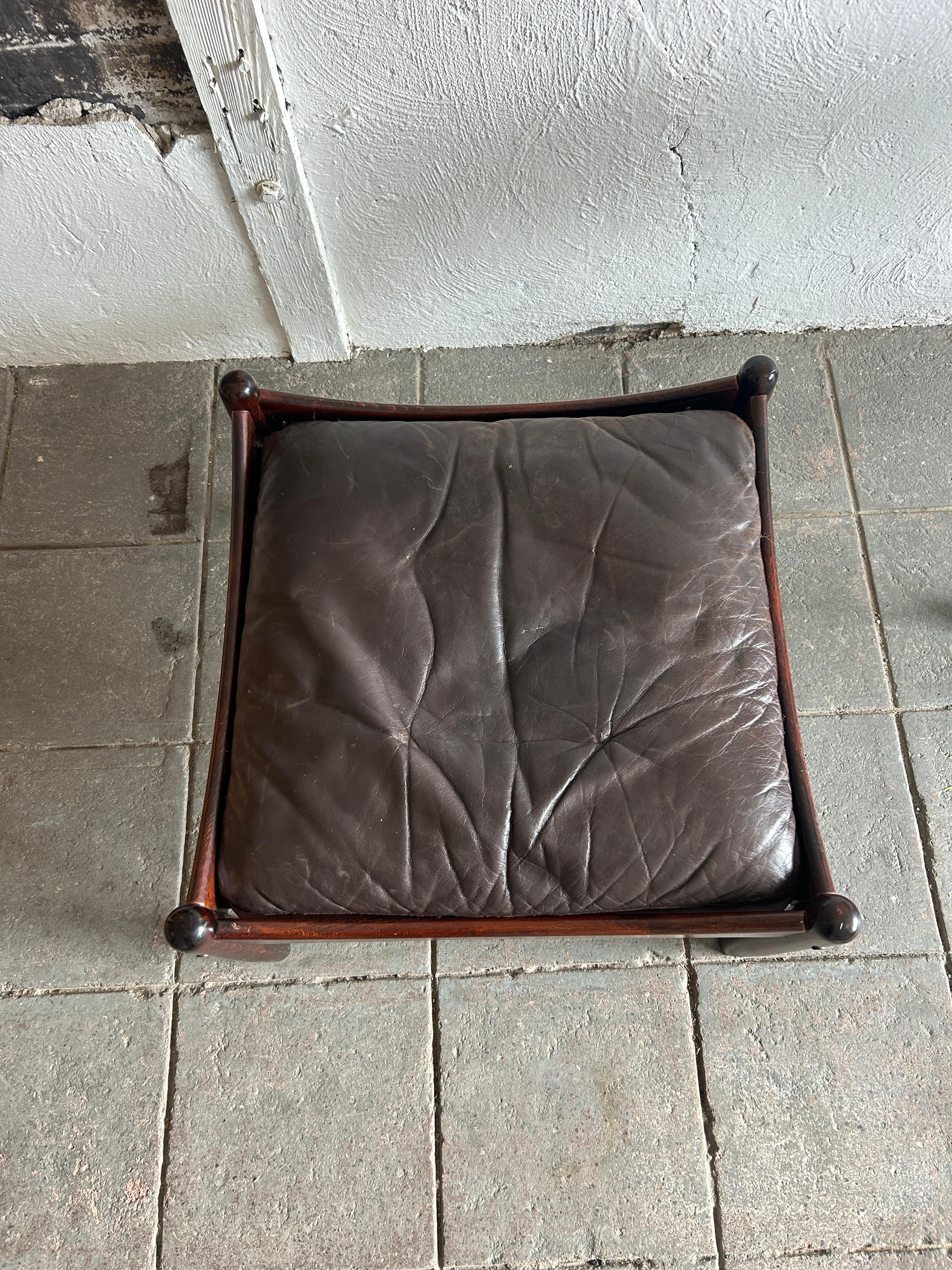 Mid century Scandinavian brown leather rosewood ottoman Norway. Brown leather cushion with rosewood legs and frame. Labeled made in Norway. Located in Brooklyn NY.

Measures 24” x 24” x 13” high