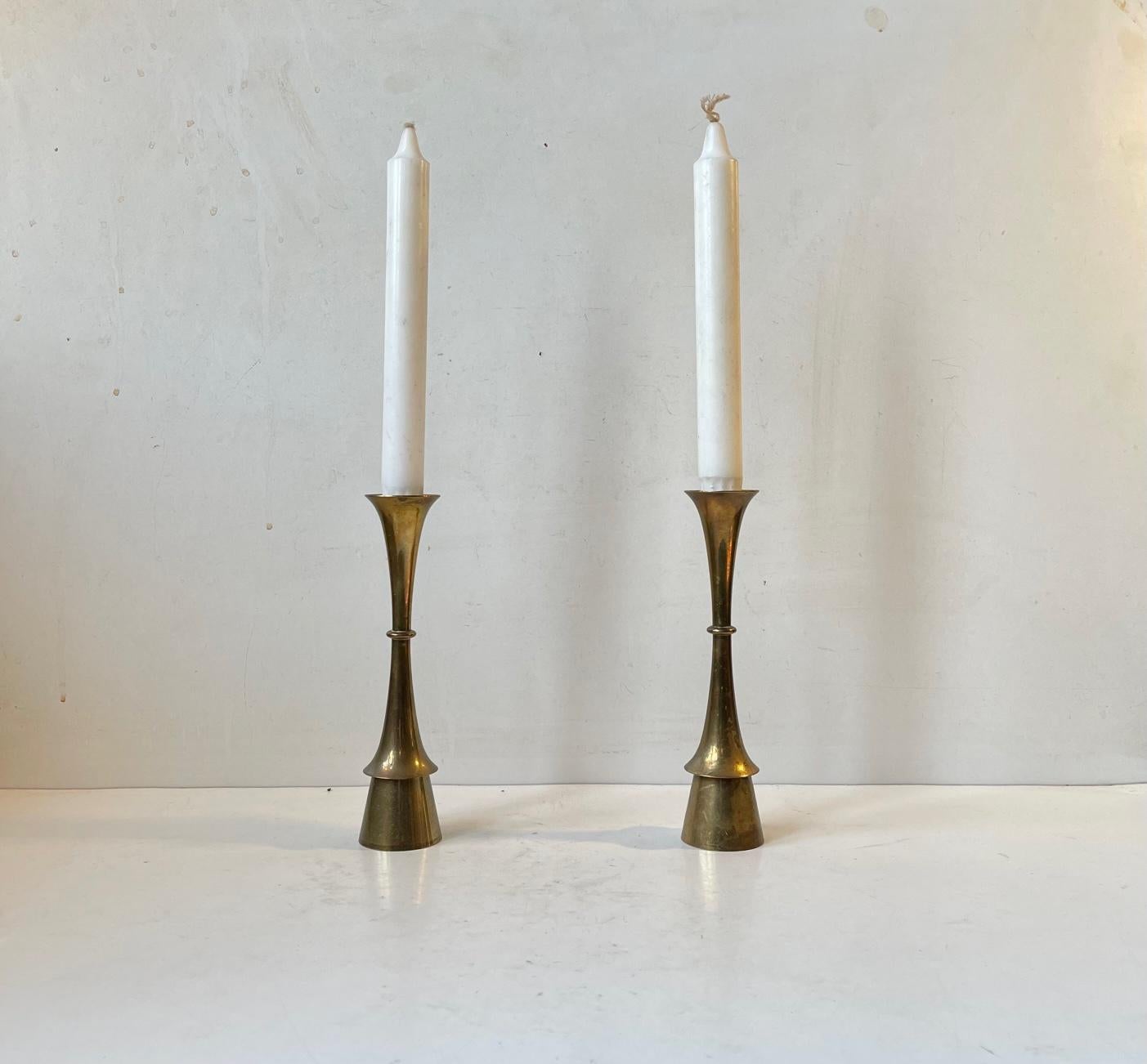 A pair of solid brass candlesticks designed and manufactured by Hyslop in Copenhagen, Denmark during the 1960s. The candlesticks are to be fitted with regular sixed candles. They have not been polished recently and display patina. The style of this