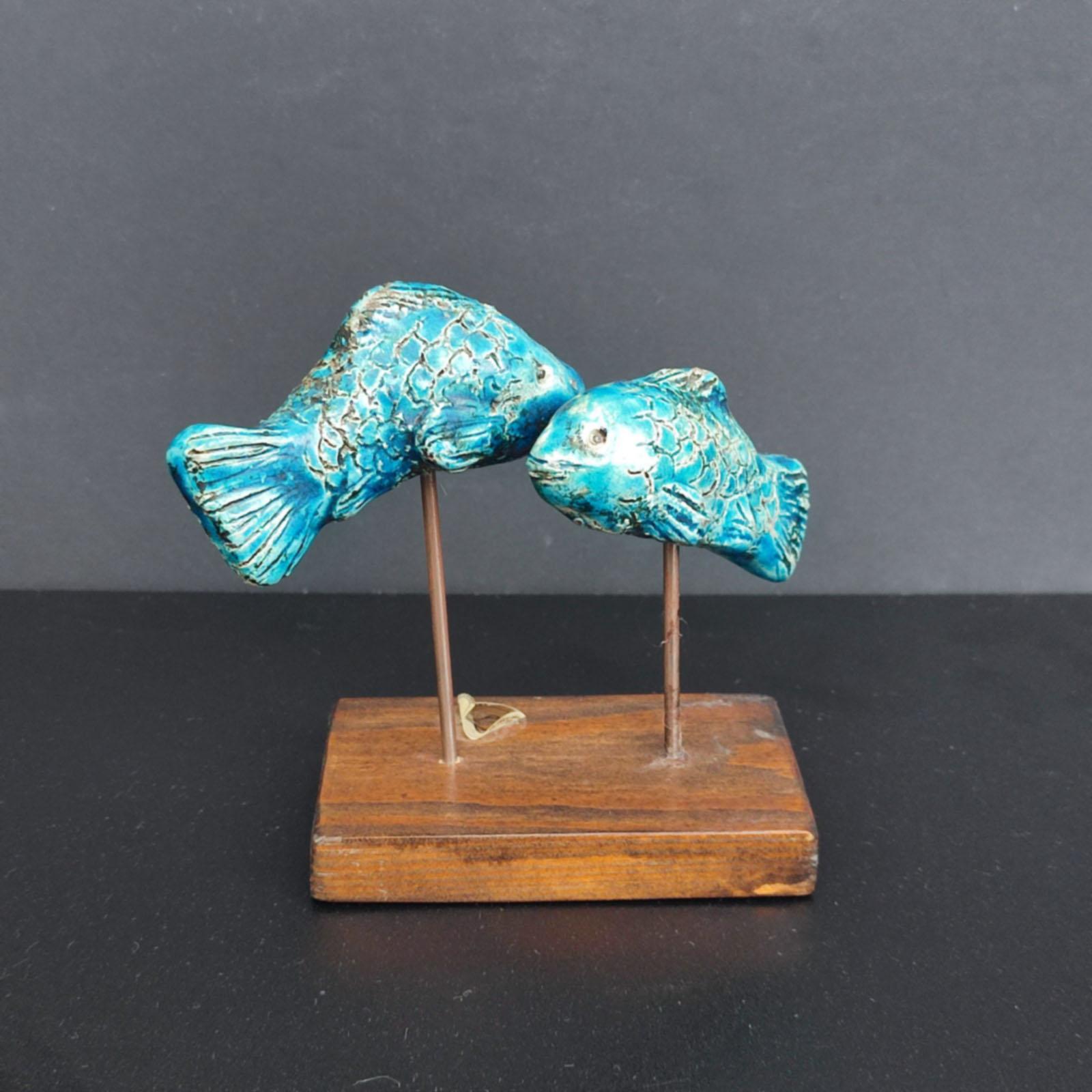 Beautiful ceramic sculpture of two fishes with a great blue glaze. An eye-catcher wherever it gets its place. Designed, modeled, fired and glazed with high-quality colors. Mounted on a wooden base. A unique piece! Original label on the