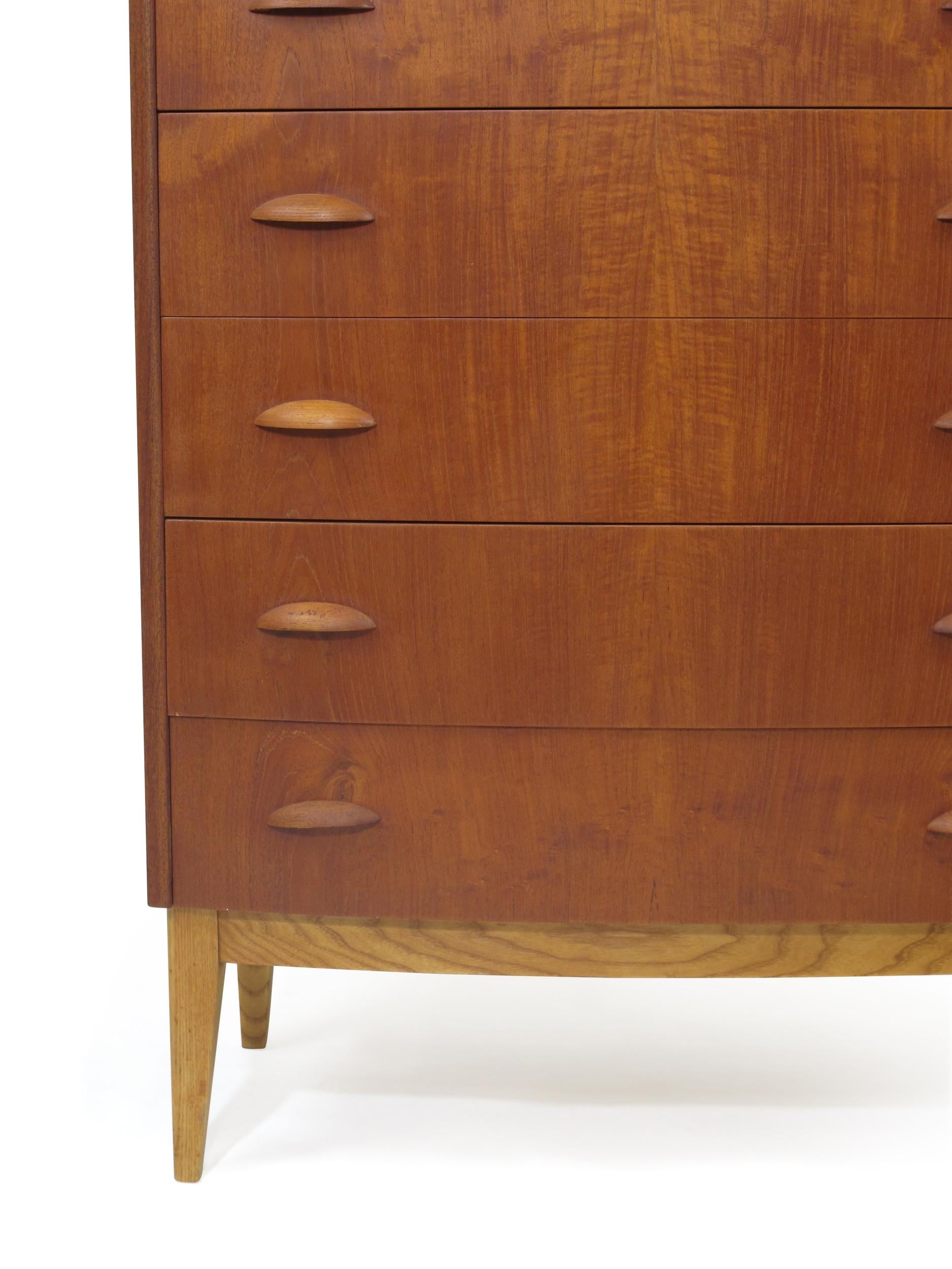 Danish six-drawer teak dresser finely crafted with a solid wood core, bow front, and sculpted pulls, raised on tapered oak legs. Finely restored with natural oil, in excellent condition.