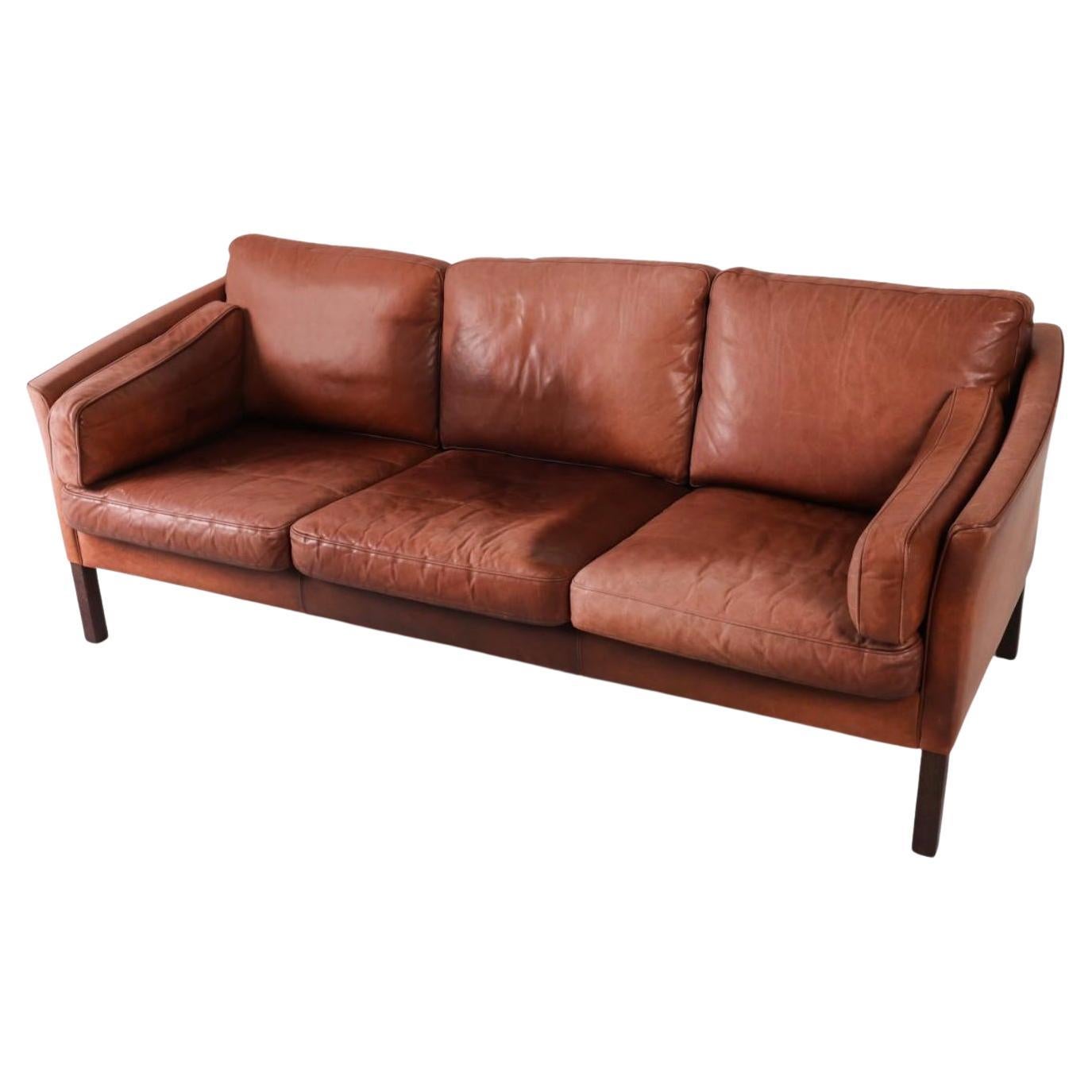 The Modern Scandinavian Scandinavian Danish Modern canapé en cuir délavé brun rougeâtre de Stouby. Canapé 3 places au design et à la forme remarquables, reposant sur 4 pieds carrés en bois de teck. Bon état vintage prêt à l'emploi. Fabriqué au