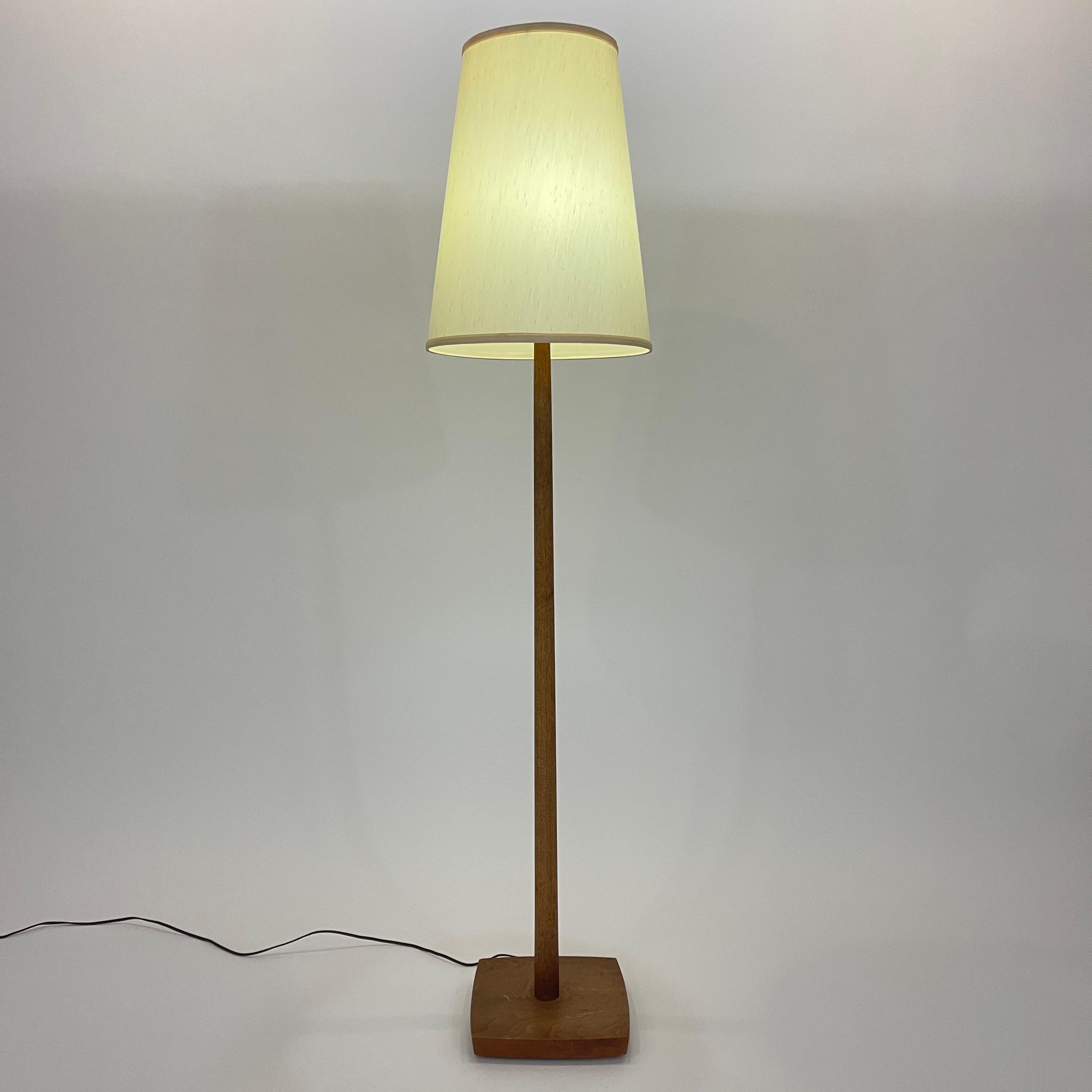 Scandinavian designer midcentury floor lamp rendered in turned teak with a curved squared base, retaining its original fabric shade. Sweden, 1960s