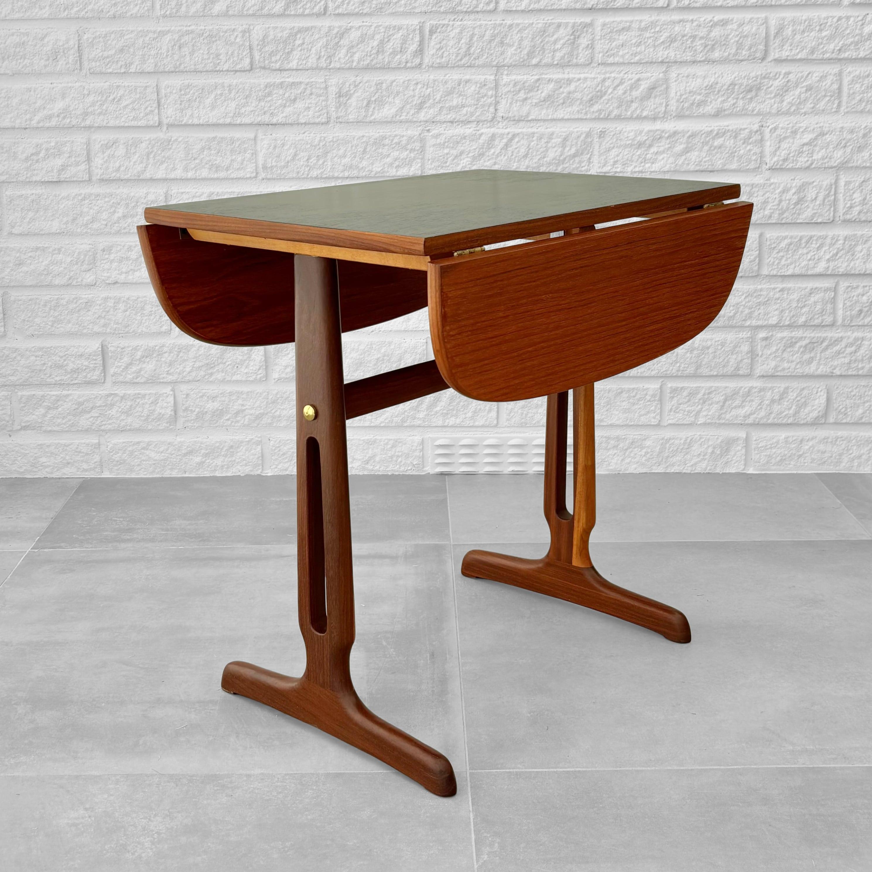 Table d'appoint ou table basse, en teck massif et placage de teck, avec des ferrures en laiton. Plateau de table légèrement ovale avec pièce centrale noire reposant sur des pieds décoratifs. Produit par un fabricant suédois non identifié dans les