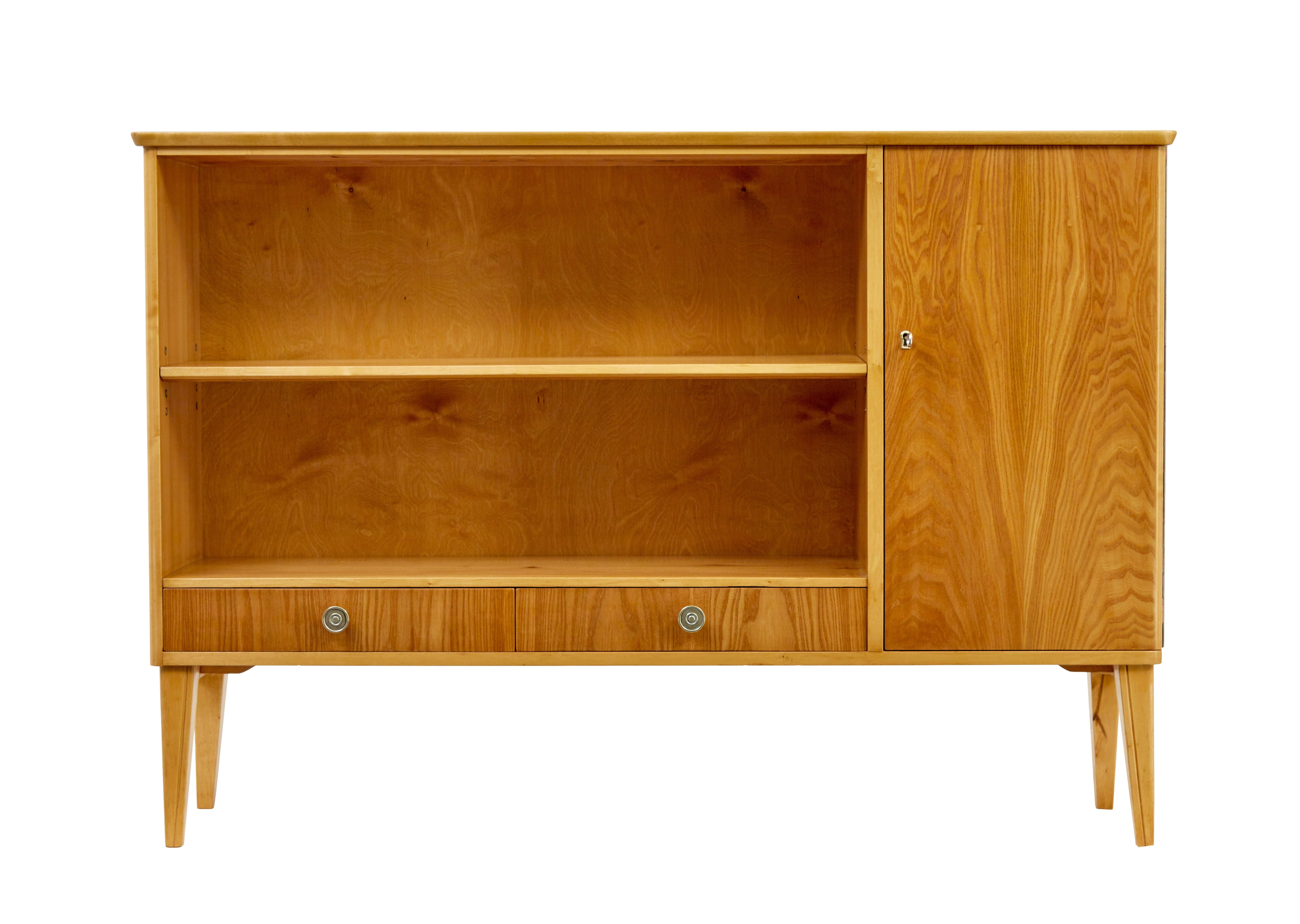 Mid century Scandinavian elm low open bookcase cabinet circa 1950.

Fine quality low open bookcase of smaller proportions fully refurbished in our workshop.

Matched veneers to the top surface, with a single door cupboard of the same manner.  Door
