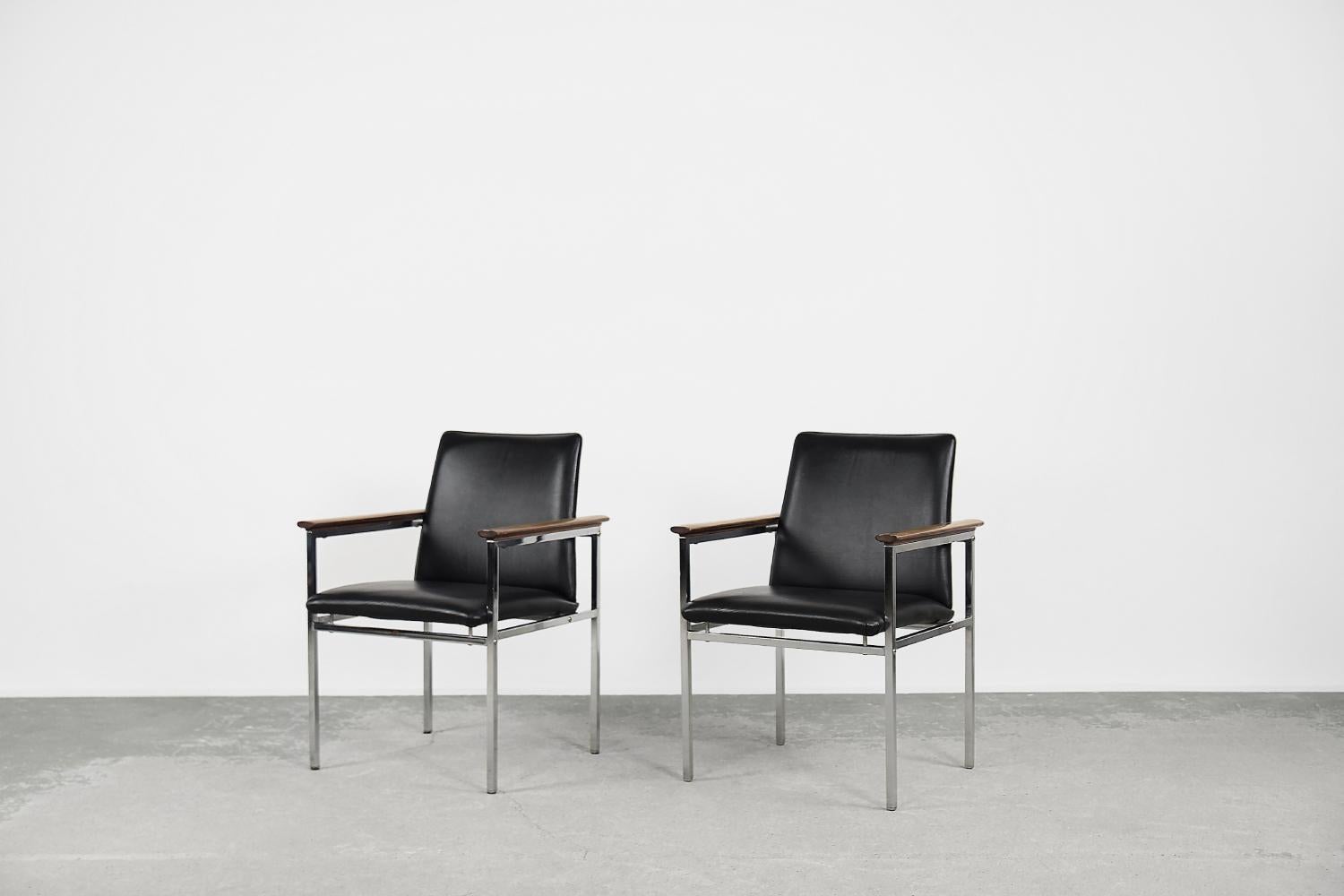 This pair of armchairs was designed by Sigvard Bernadotte for the Danish manufacturer France & Søn during the 1960s. The geometric frame of the armchairs is made of chrome-plated metal. The seat and the backrest are upholstered with black leather.