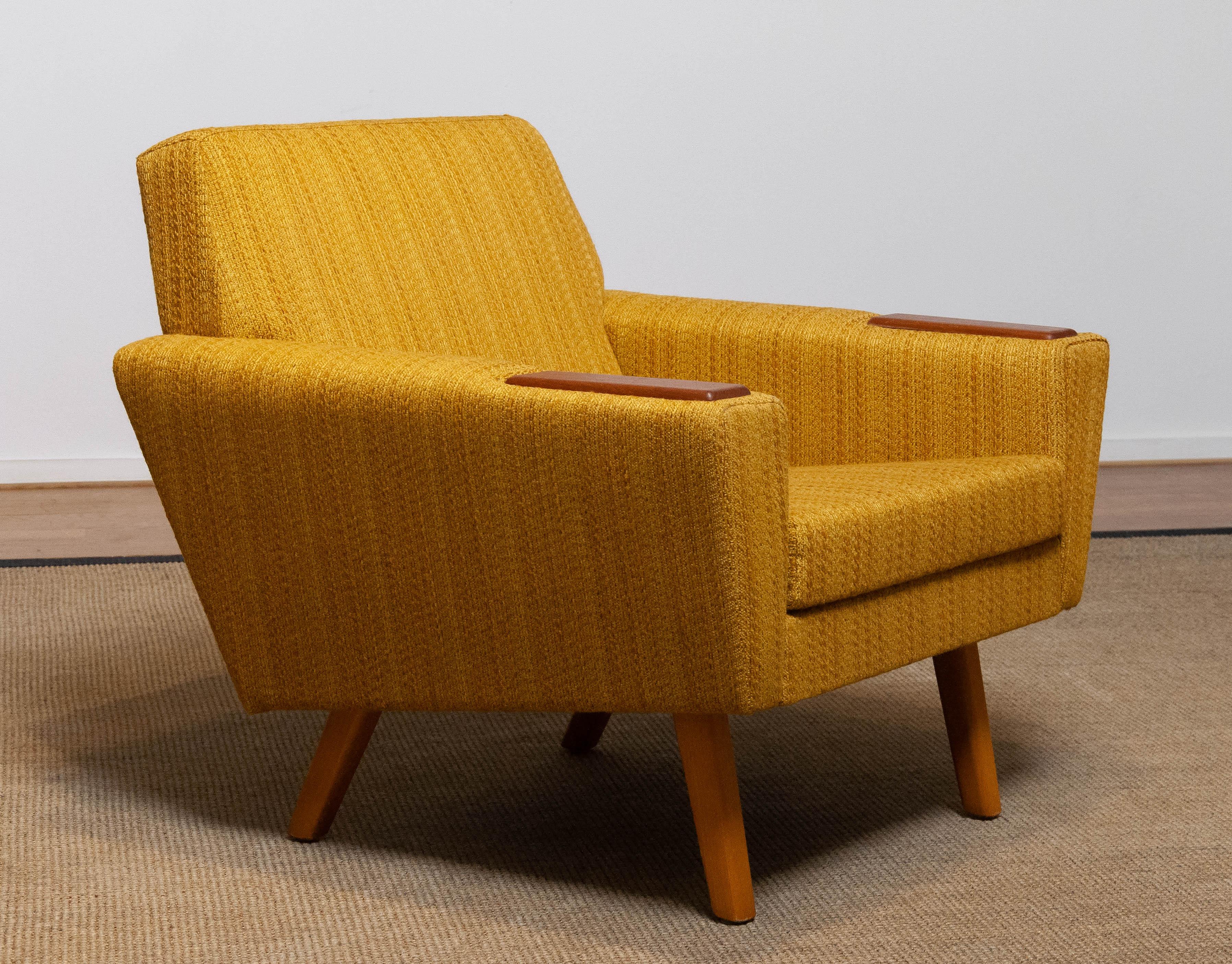 Absolutely beautiful and typical Scandinavian mid century lounge chair in yellow / ocher and a little brown blended colored woolen fabric in complete original condition. This chair supports and sits very good and is in allover very good condition as