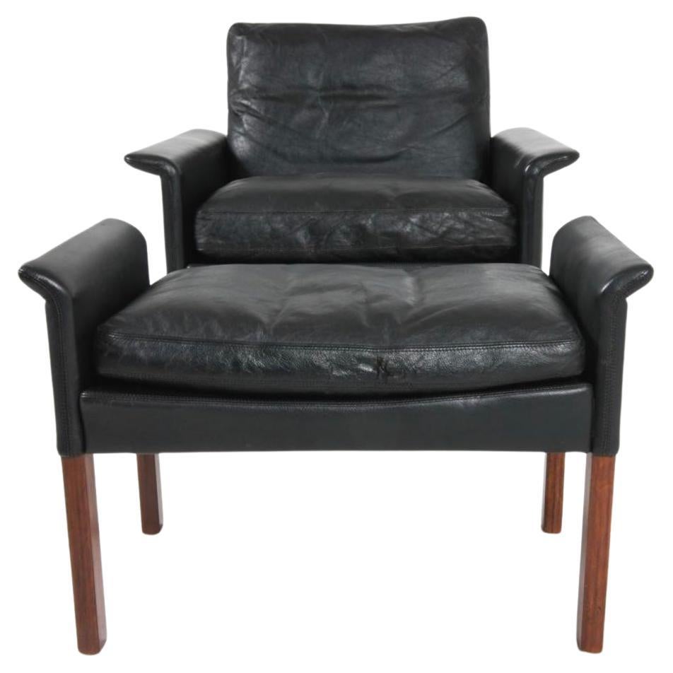 Precioso sillón moderno escandinavo de cuero negro con otomana diseñado por Hans Olsen. Todos los cojines originales de suave cuero negro rellenos de plumón. La silla está en buen estado vintage todas las correas están bien con patas de palisandro