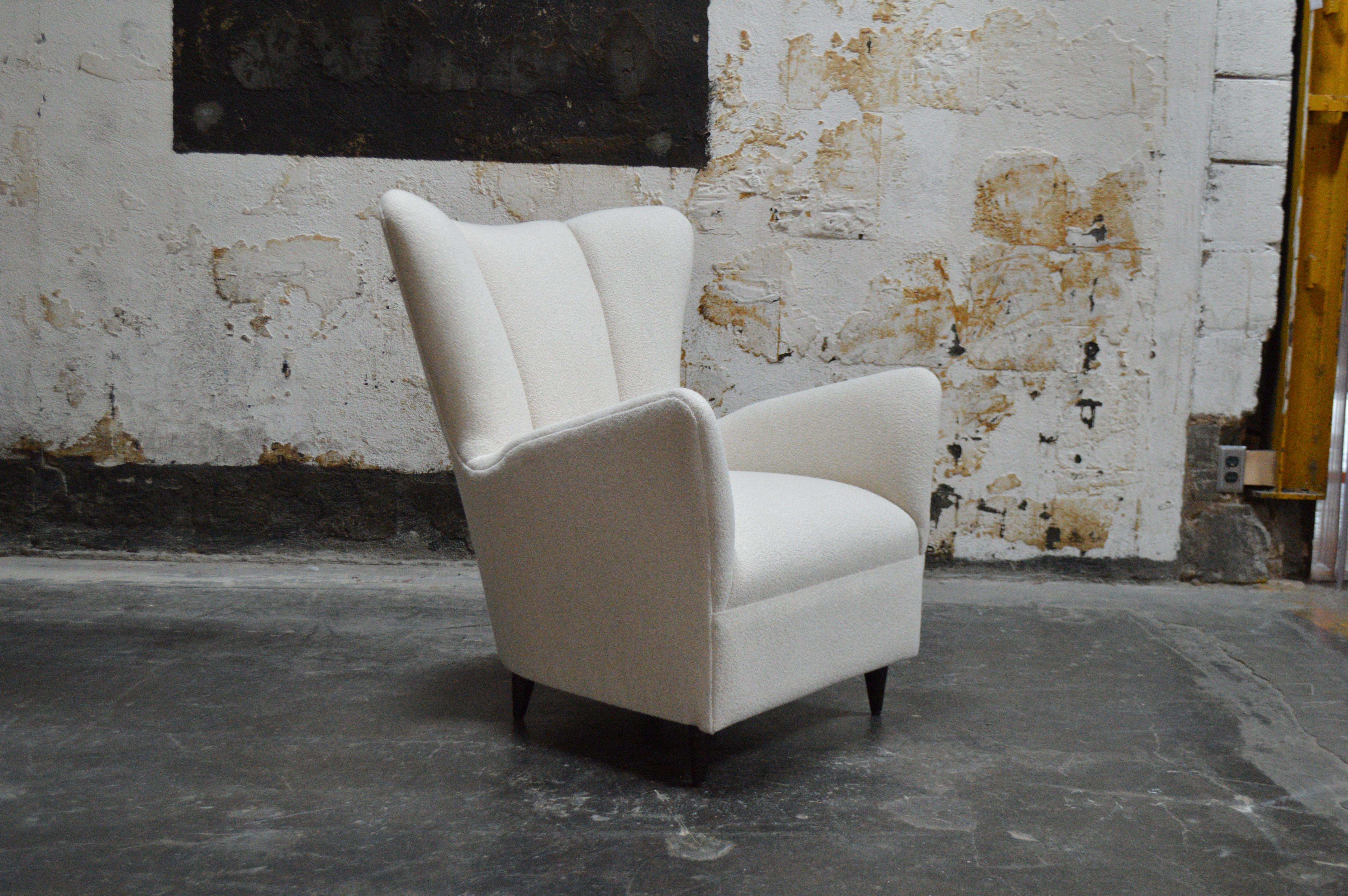 This impressive Scandinavian Modern chair features a tall channeled back, newly restored upholstery, and sturdy wooden legs. It has been restored and reupholstered in an off white bouclé fabric. This comfortable chair would make a great addition to
