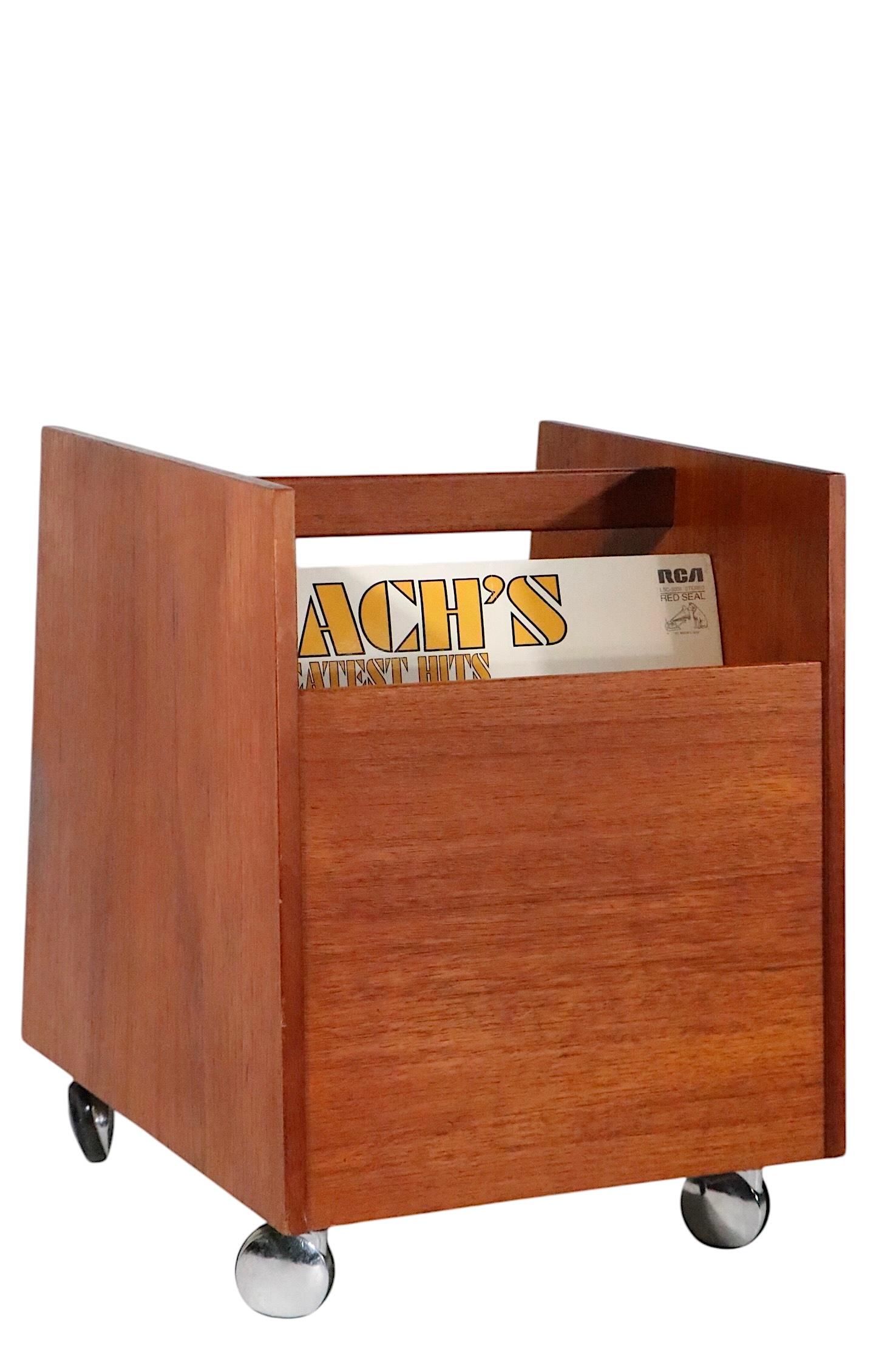 Revistero moderno escandinavo de mediados de siglo, caddy para álbumes de discos, fabricado en Noruega, diseñado por Rolf Hesland, para Brucksbo, c. 1960. La caja de teca y chapa de teca está montada sobre sus patas originales de cromo y ruedas