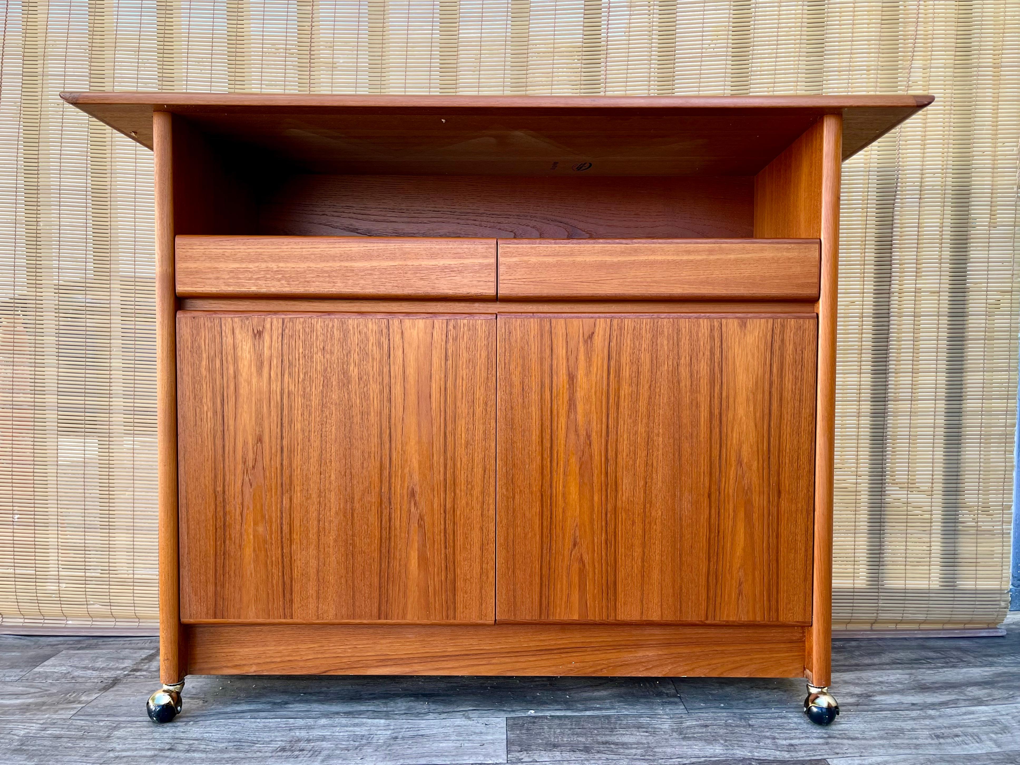 Vintage Mid-Century Scandinavian Modern Style Teak Server / Dry Bar with Casters by Nordic Furniture of Ontario, Canada. Circa 1980s
Features a sleek minimalist design, a long shelf with two silverware drawers, two cabinets with adjustable shelves,