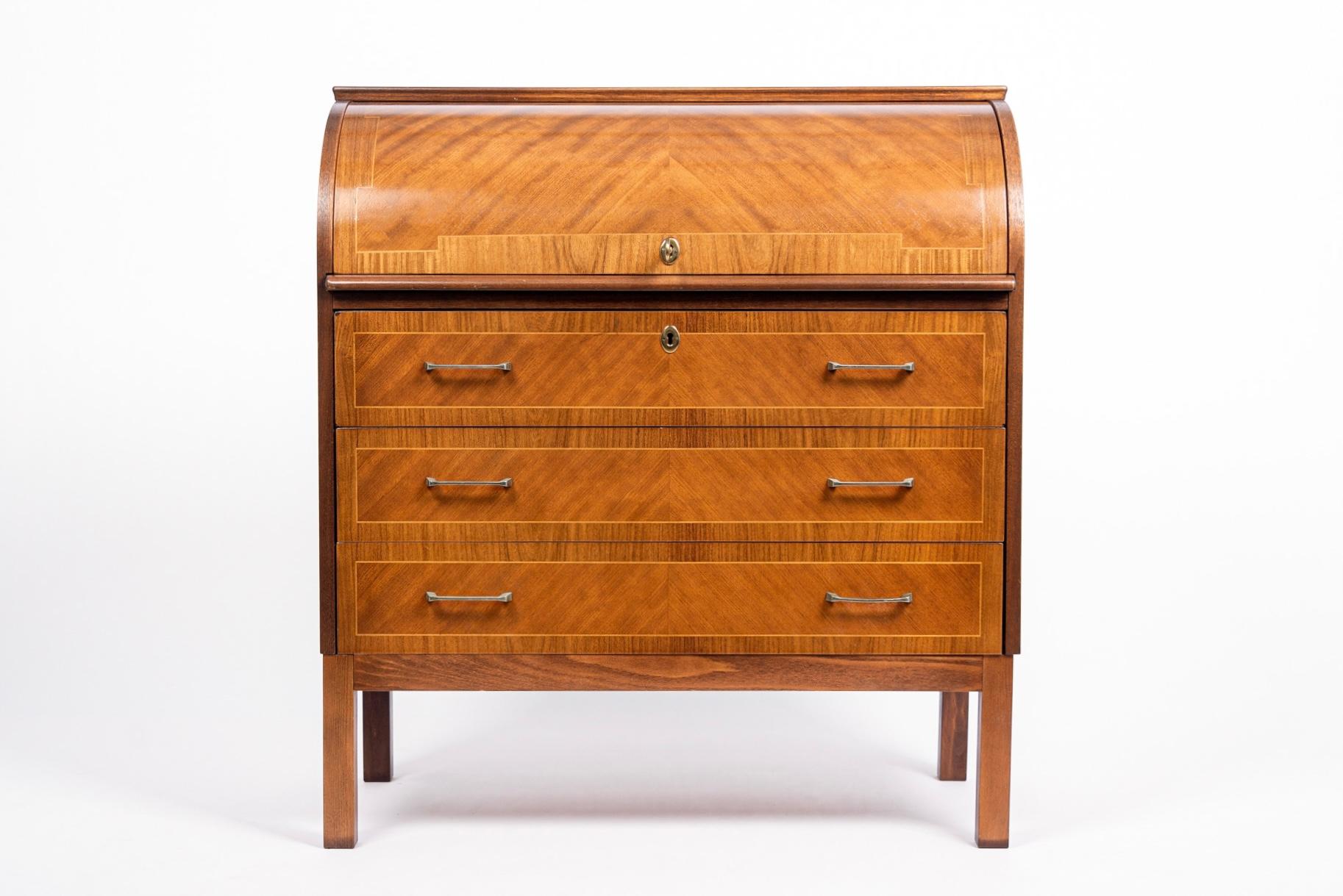 This vintage mid century Swedish modern two-toned cylinder secretary desk cabinet circa 1960 has a classic Scandinavian modern design with clean minimalist lines and features a stunning inlaid veneer design. The rolltop opens on a top compartment